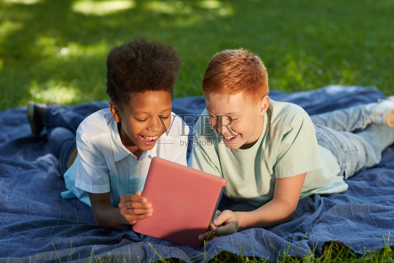 在公园里使用平板电脑的男孩照片摄影图片