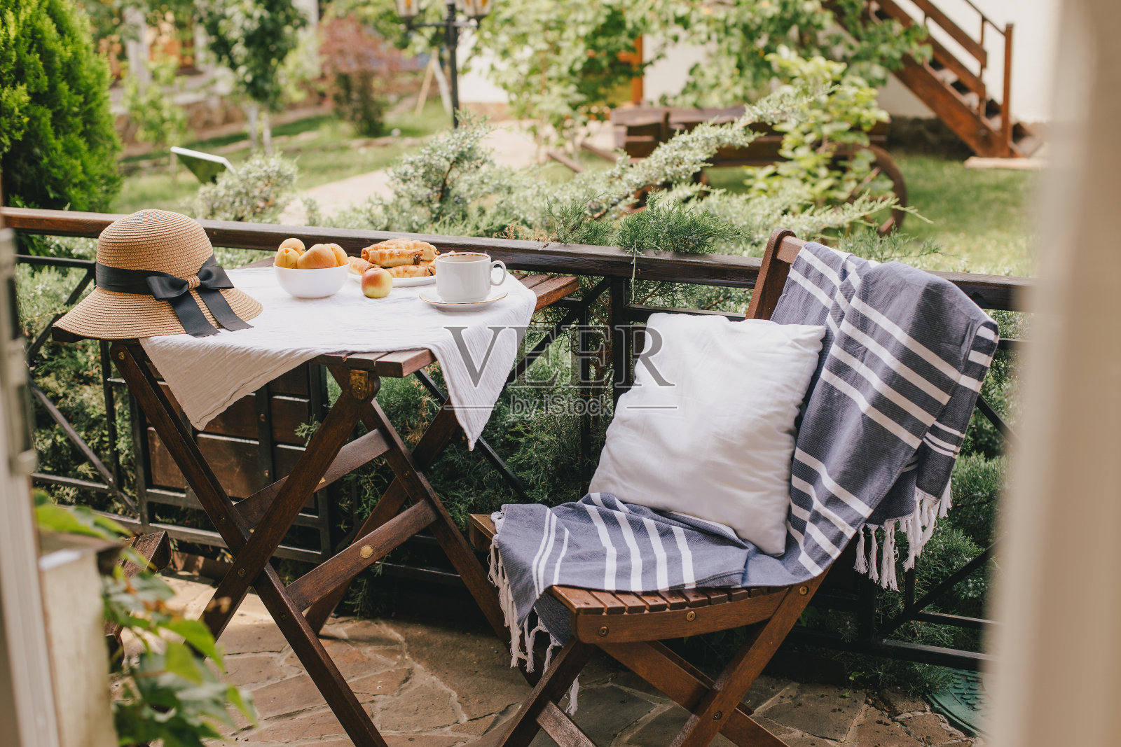 早餐,新鲜的茶,水果和饼干在户外舒适的阳台上的乡村别墅或别墅与花园的观点。照片摄影图片
