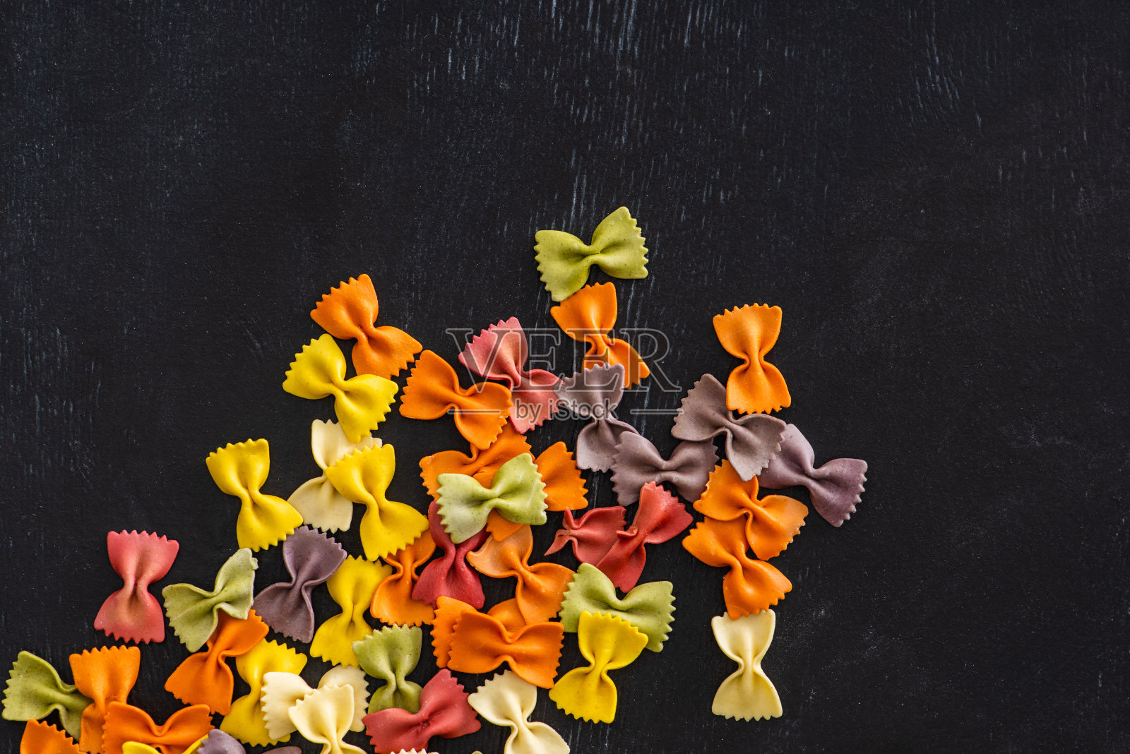 顶视图的彩色生farfall意大利面在黑色的木制背景照片摄影图片