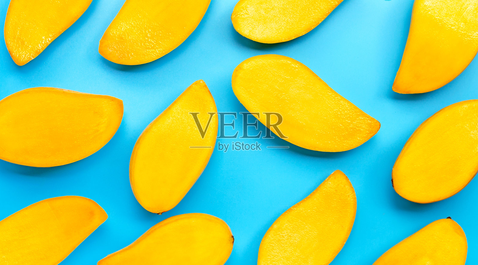 热带水果,蓝色背景上的芒果片。照片摄影图片