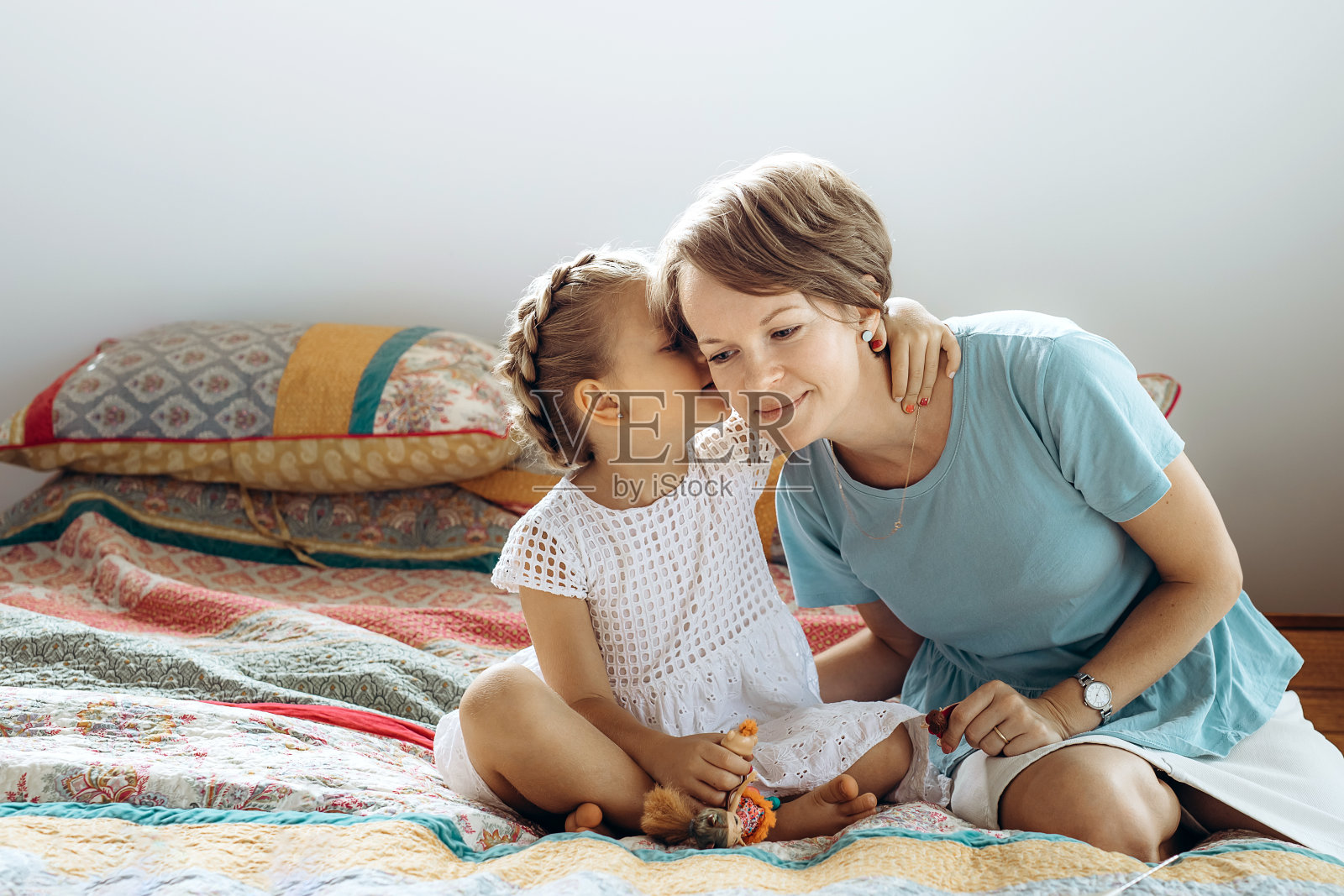 妈妈和她的小女儿在床上聊天。那女孩在妈妈耳边说了些什么照片摄影图片
