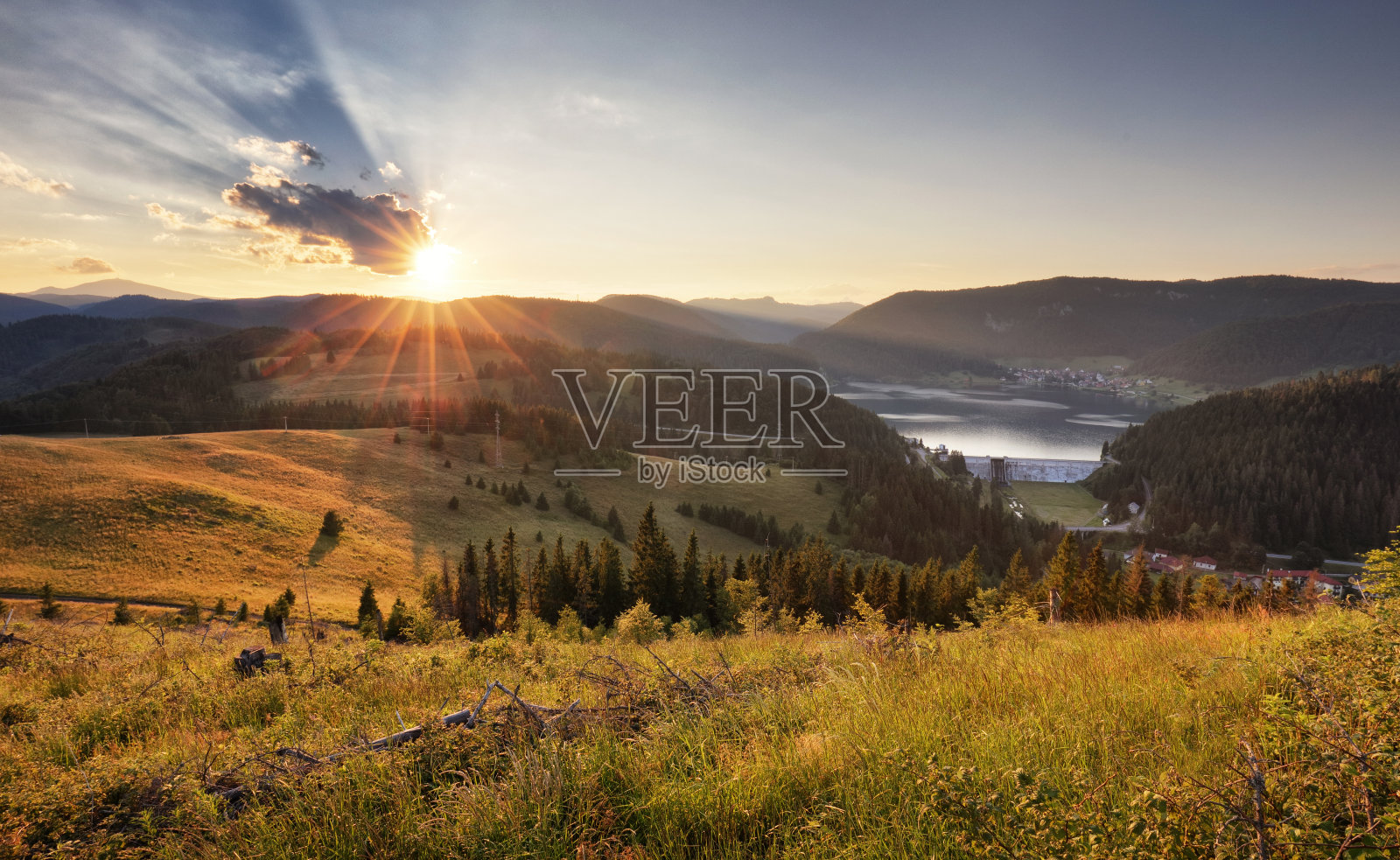景观有阳光、草地、森林和山脉。照片摄影图片
