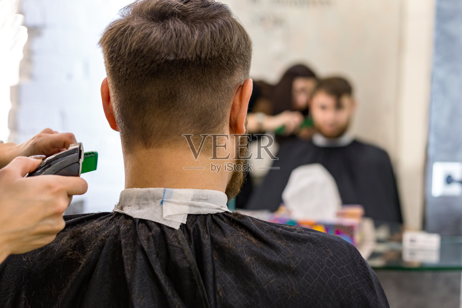 美发师为男性客户理发,有胡子的男士使用专业美发师工具,设备放在美发师工作空间、工作场所。理发师的服务。去理发店理发,修胡子。照片摄影图片