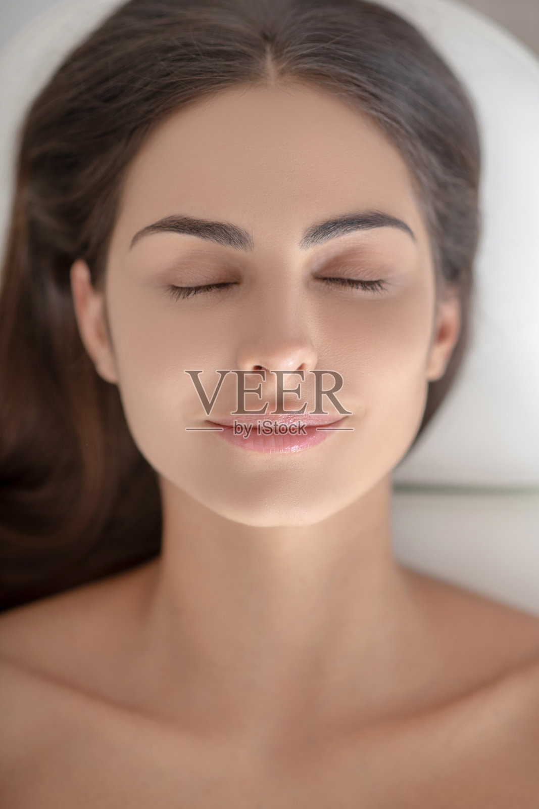 年轻女子闭着眼睛躺着,看起来很放松照片摄影图片