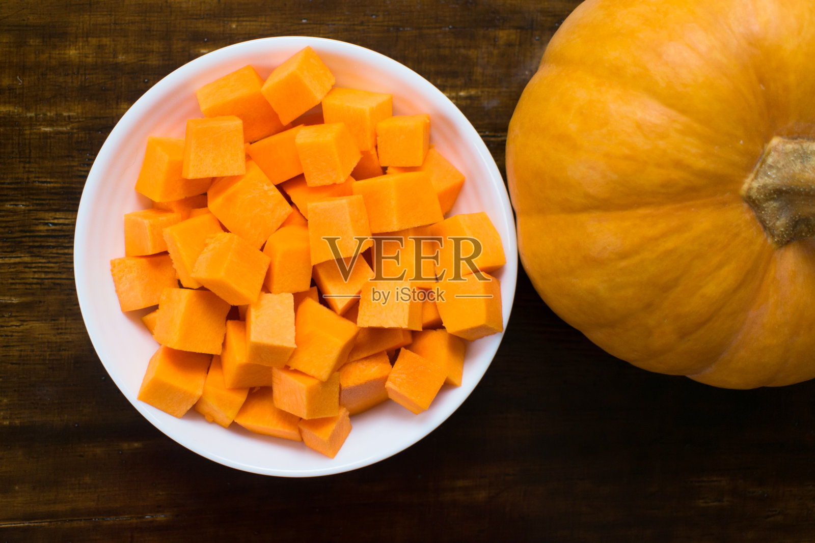 木片背景上的白色盘子里的秋南瓜片。前视图。照片摄影图片