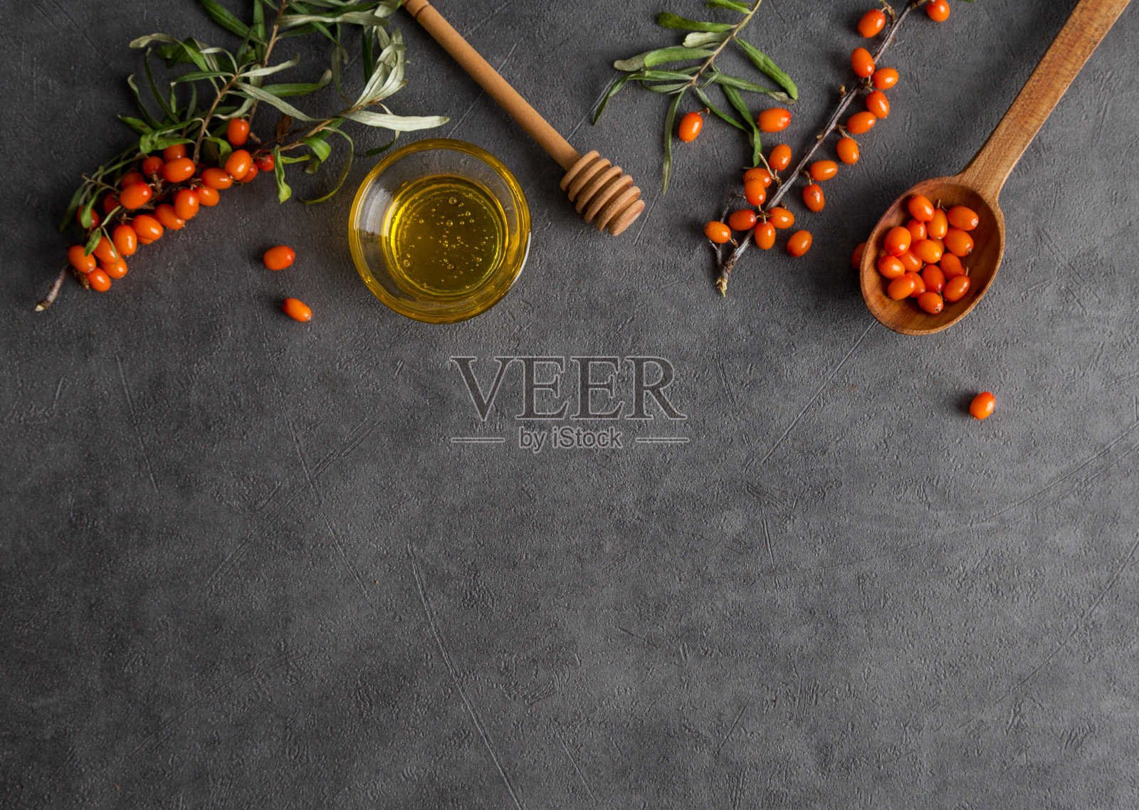 顶部视图与沙棘树枝和蜂蜜在深灰色的背景照片摄影图片