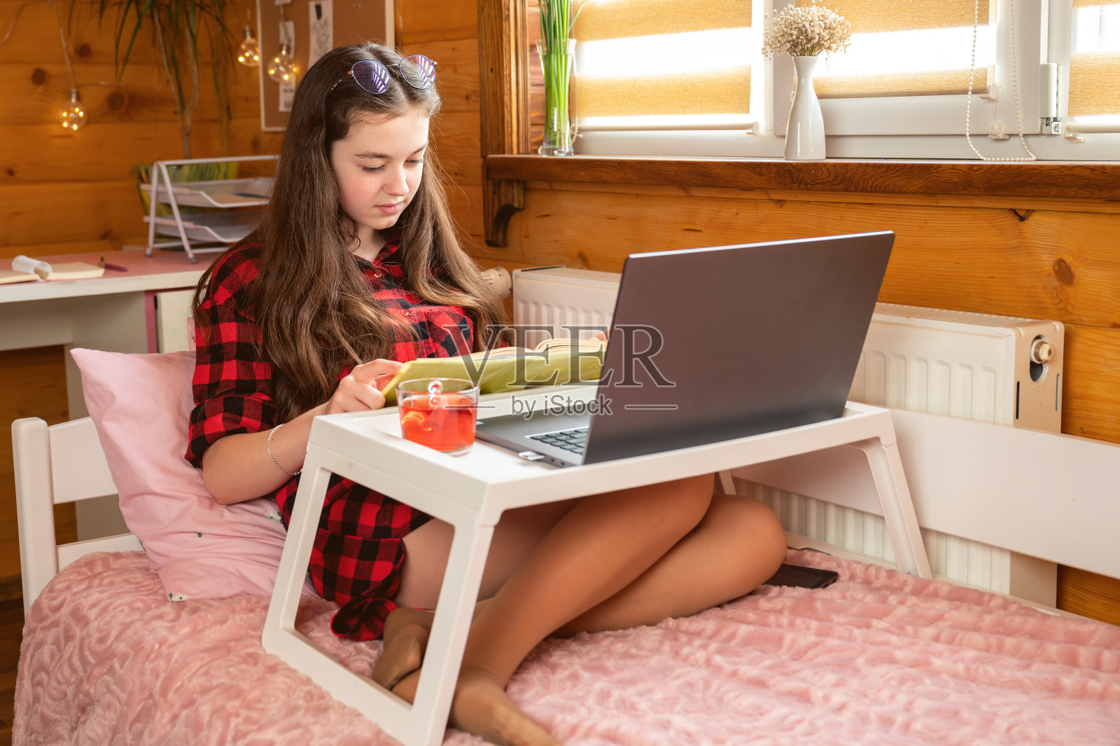 一个年轻的女学生在家里舒适的床上学习功课。照片摄影图片