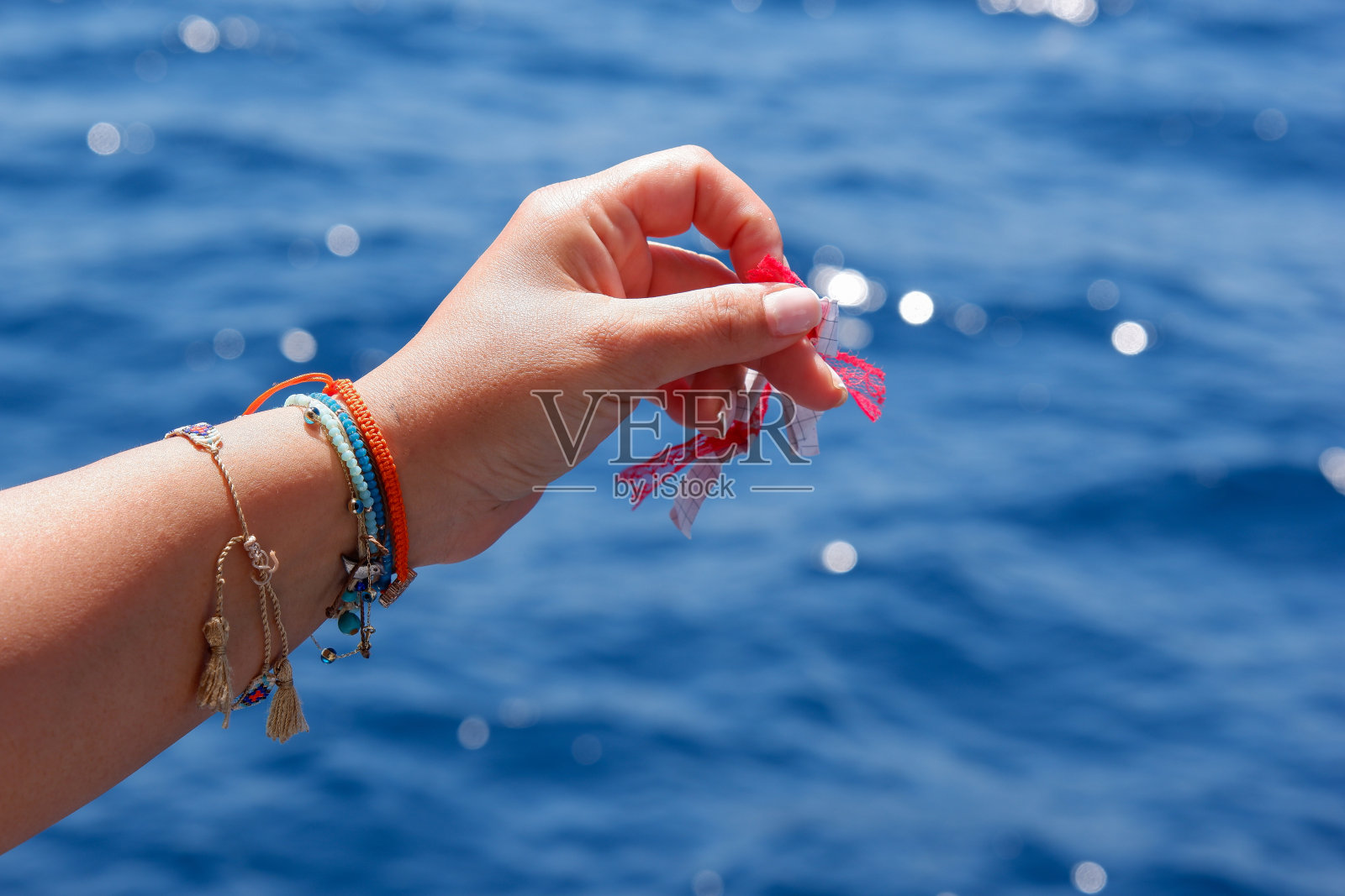 女人的手把她写在纸上的愿望扔进海里。照片摄影图片