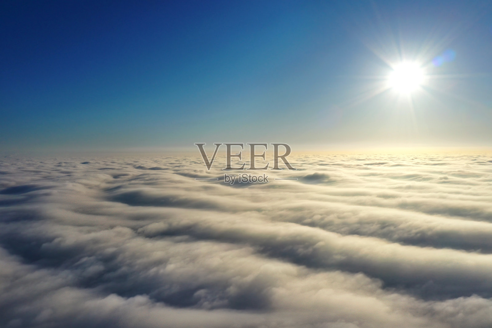 航拍,明亮的太阳在地平线上,乌云在深蓝色的天空之上。照片摄影图片