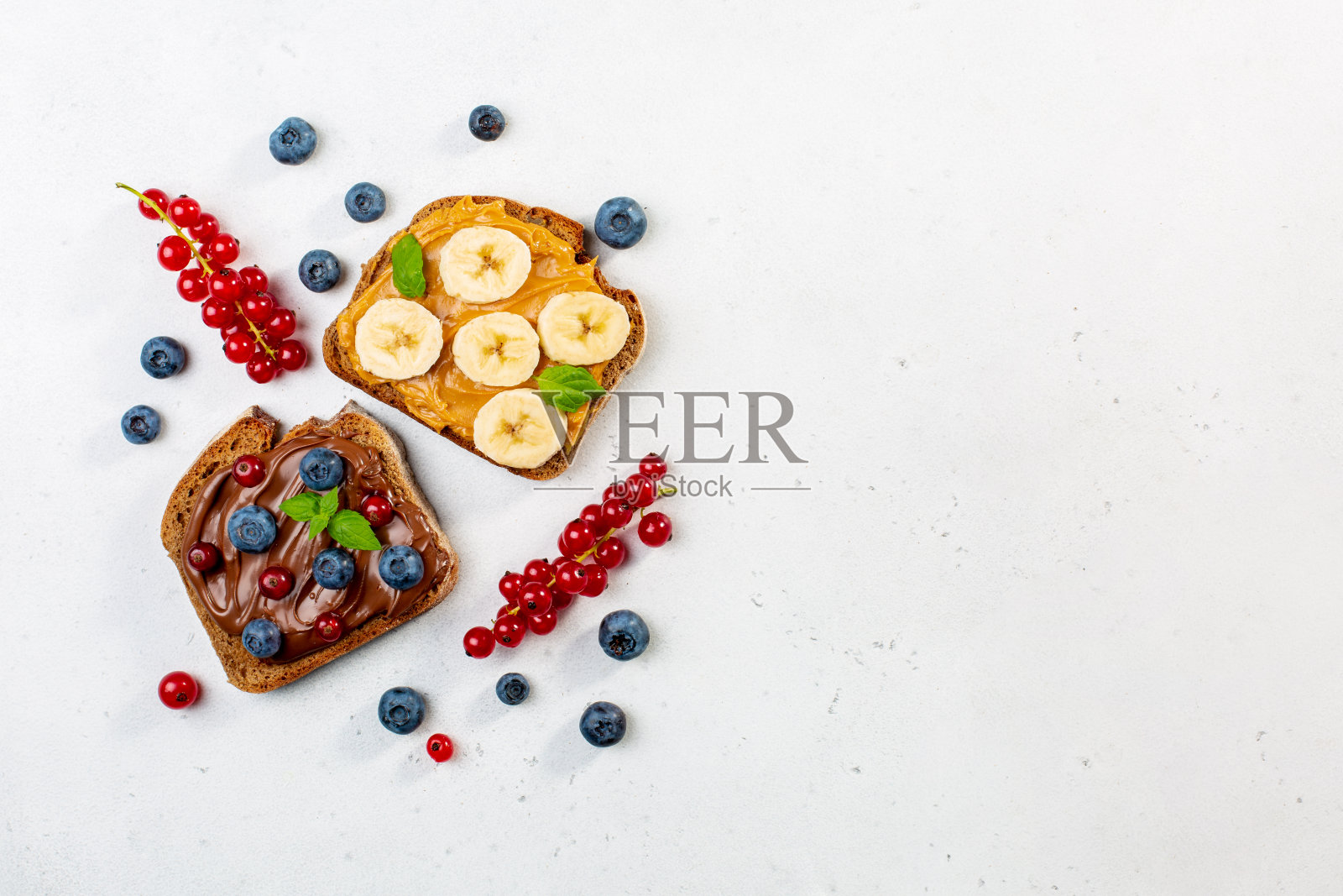 花生黄油和巧克力黄油的甜三明治装饰香蕉,浆果,薄荷。副本的空间。照片摄影图片