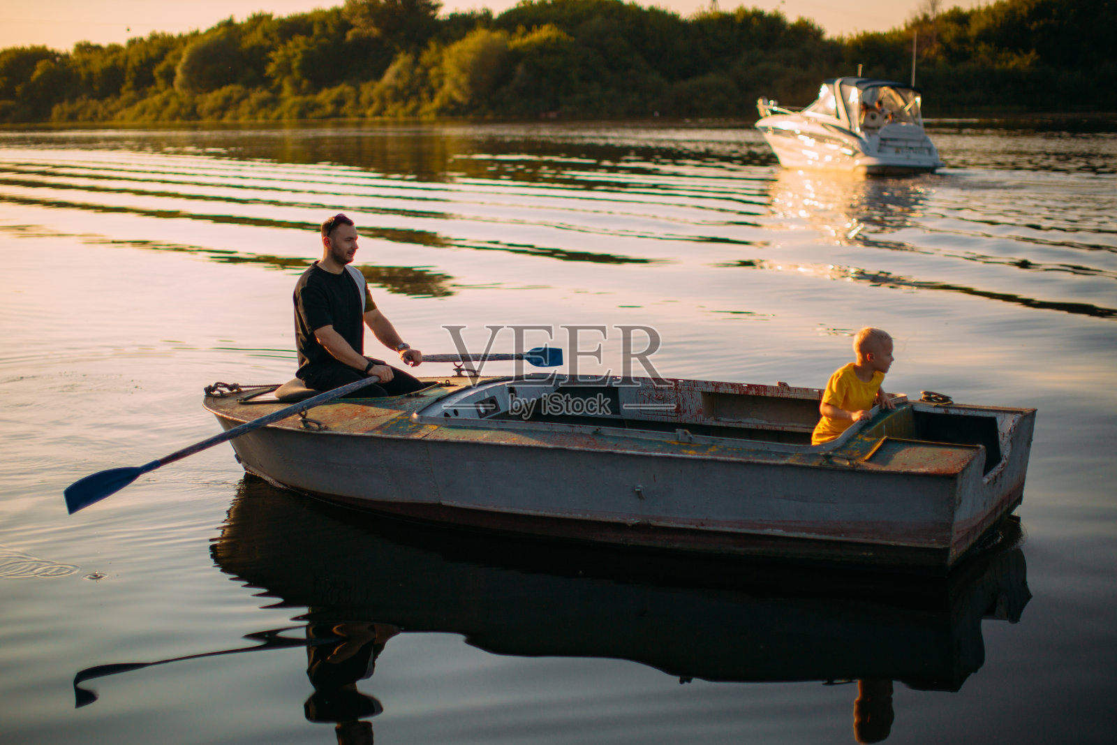 夏天父亲和儿子坐船在河或湖上。为广告或博客拍摄有关家庭和旅行的照片照片摄影图片