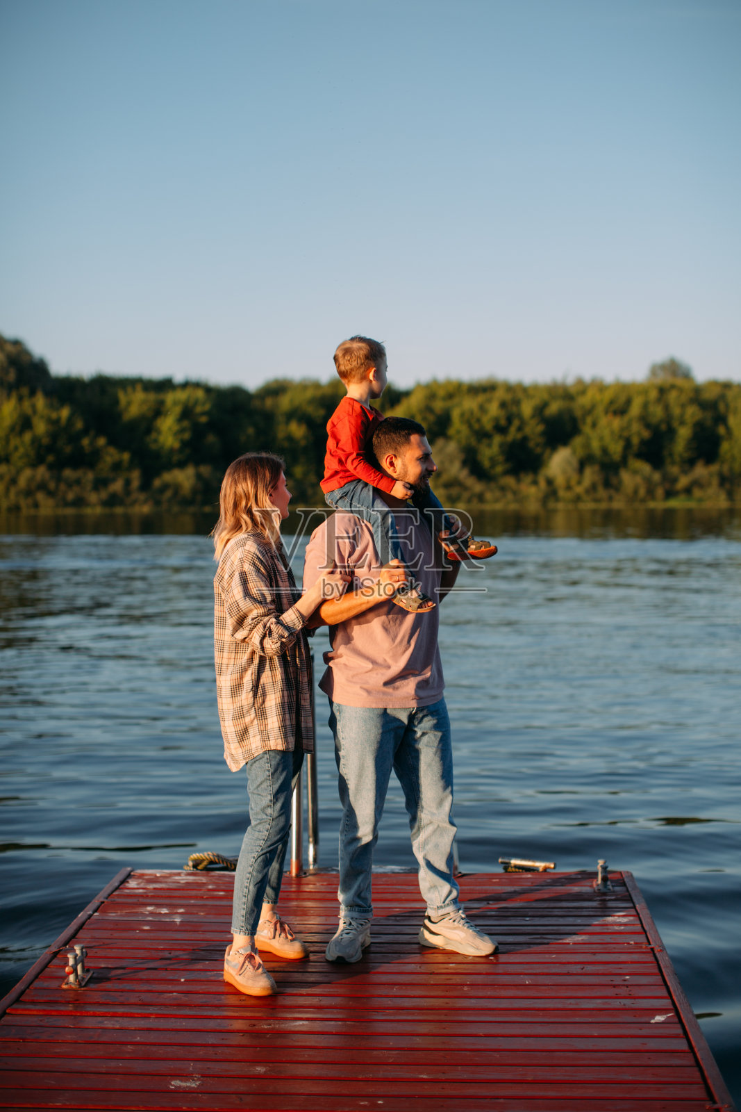 幸福的一家人站在码头上互相拥抱。为博客或广告拍摄关于家庭和旅行的夏季摄影照片摄影图片