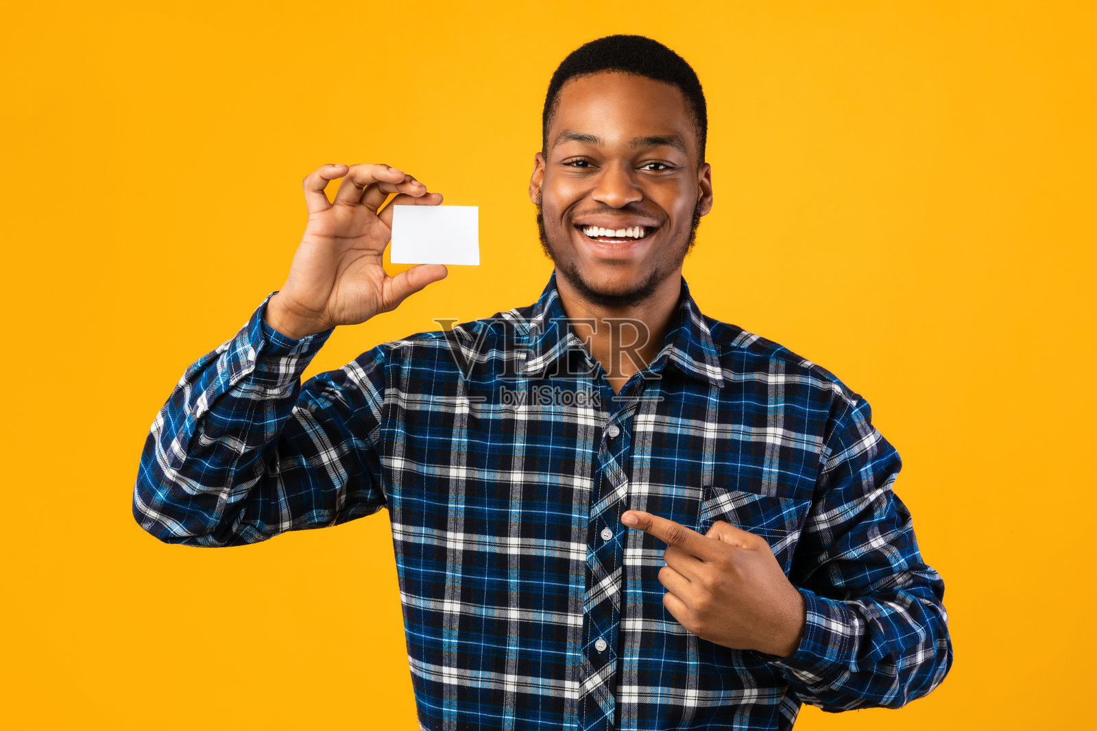 一个黑人拿着空白名片站在黄色背景上照片摄影图片