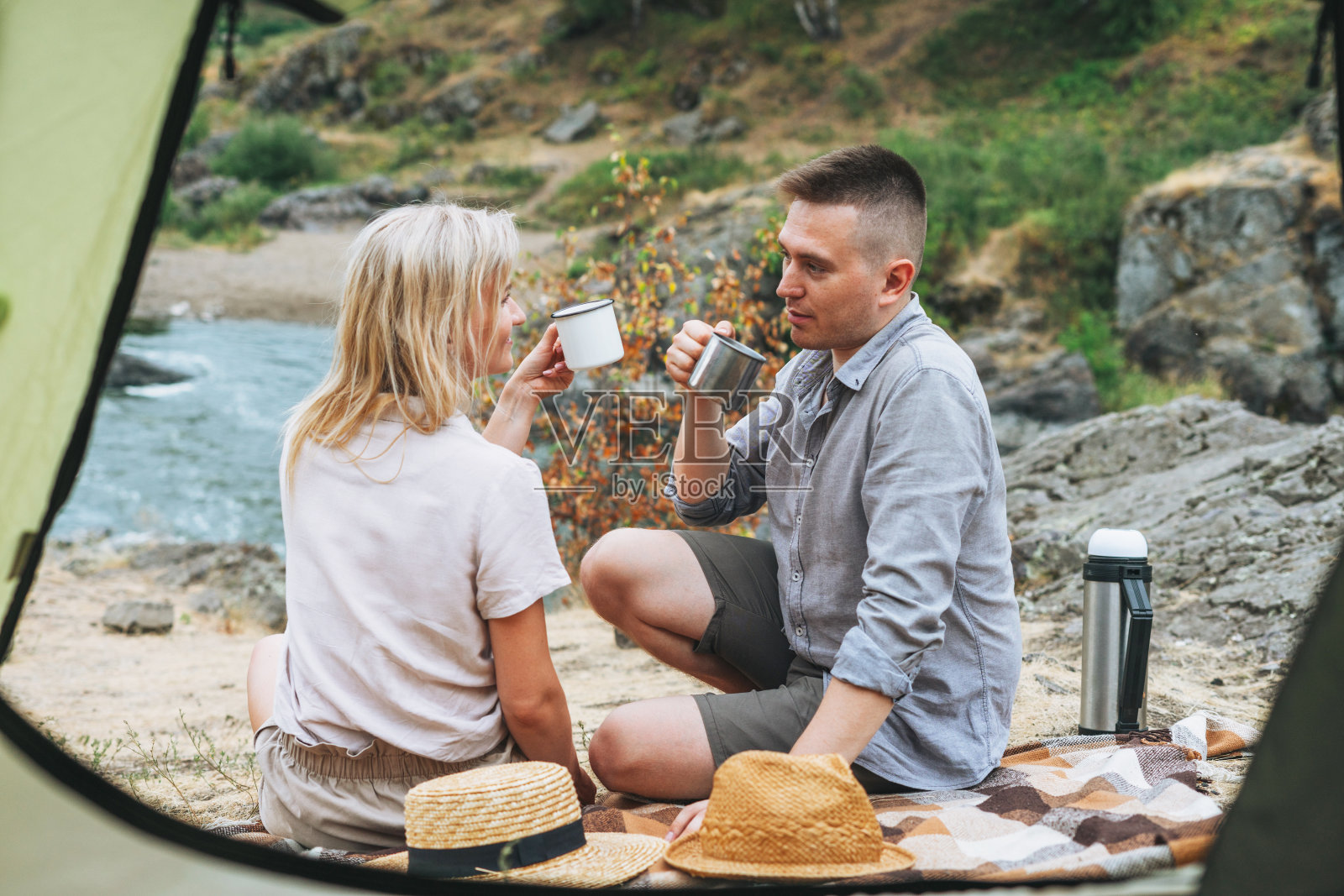 快乐的年轻夫妇旅行者在休闲的服装有午餐附近的帐篷在山上。当地旅游,周末旅行照片摄影图片