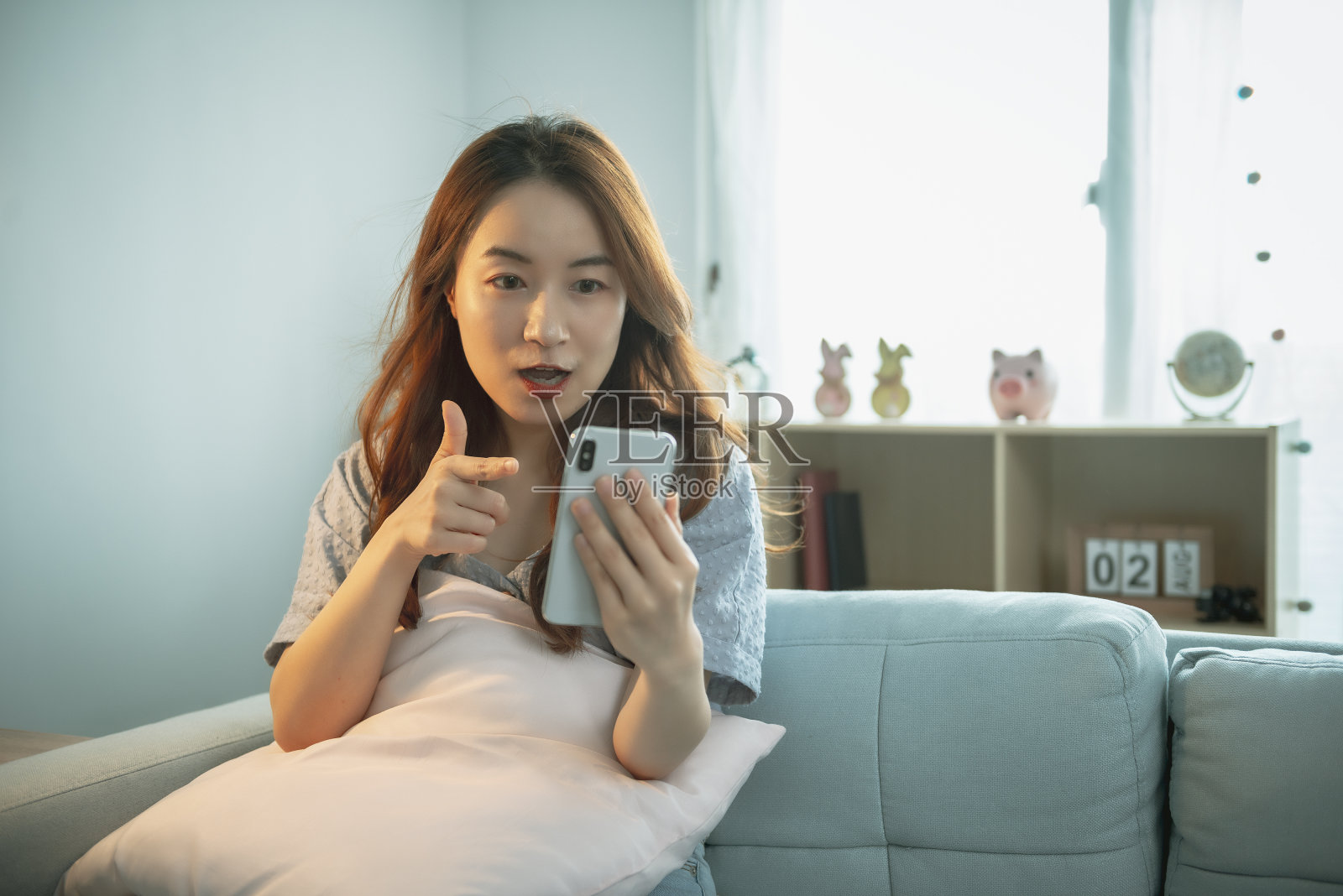 坐在沙发沙发上玩手机的女人照片摄影图片