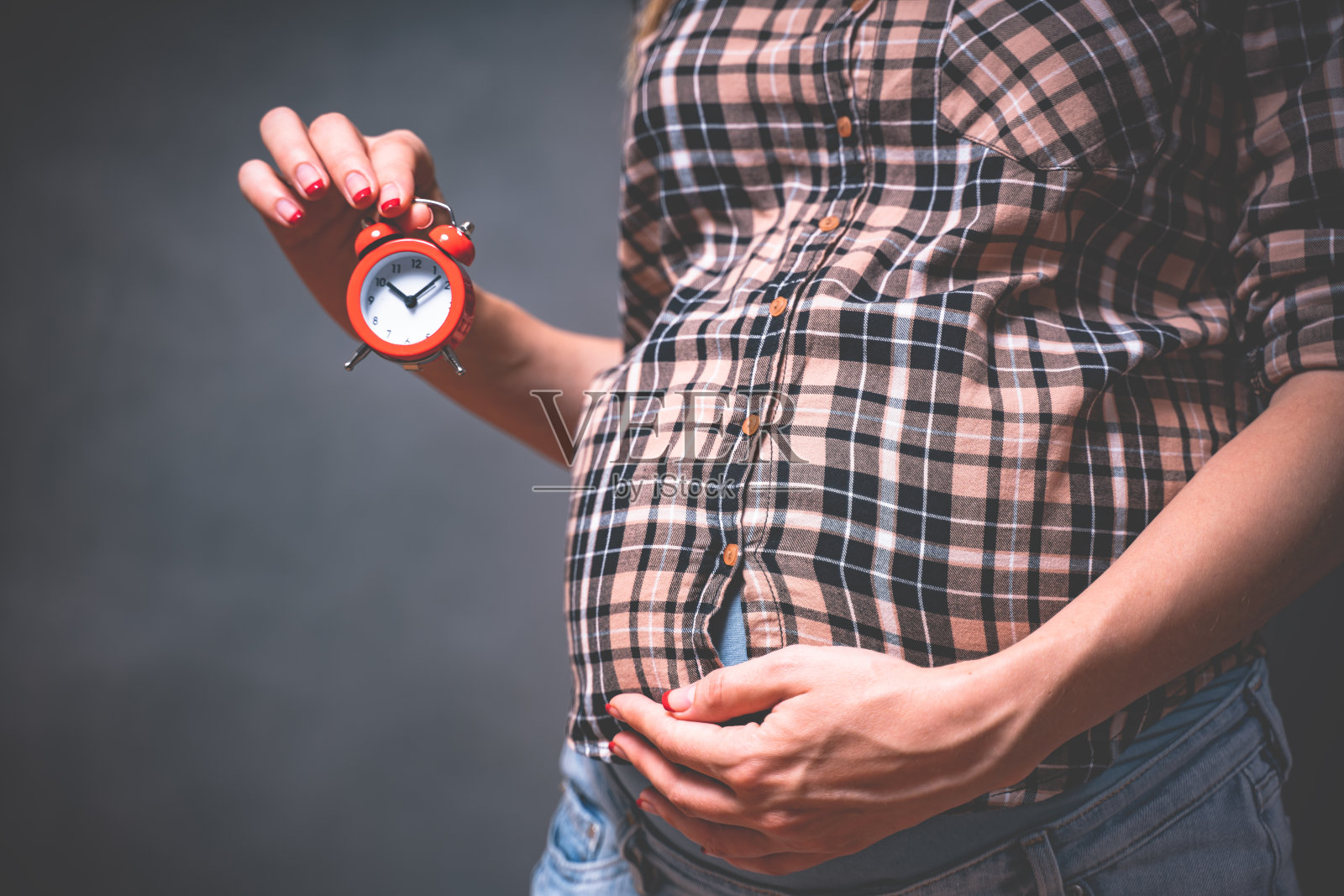 怀孕时间观念、母性观念、人与期望观念。怀孕的照片。一个孕妇拿着一个时钟照片摄影图片