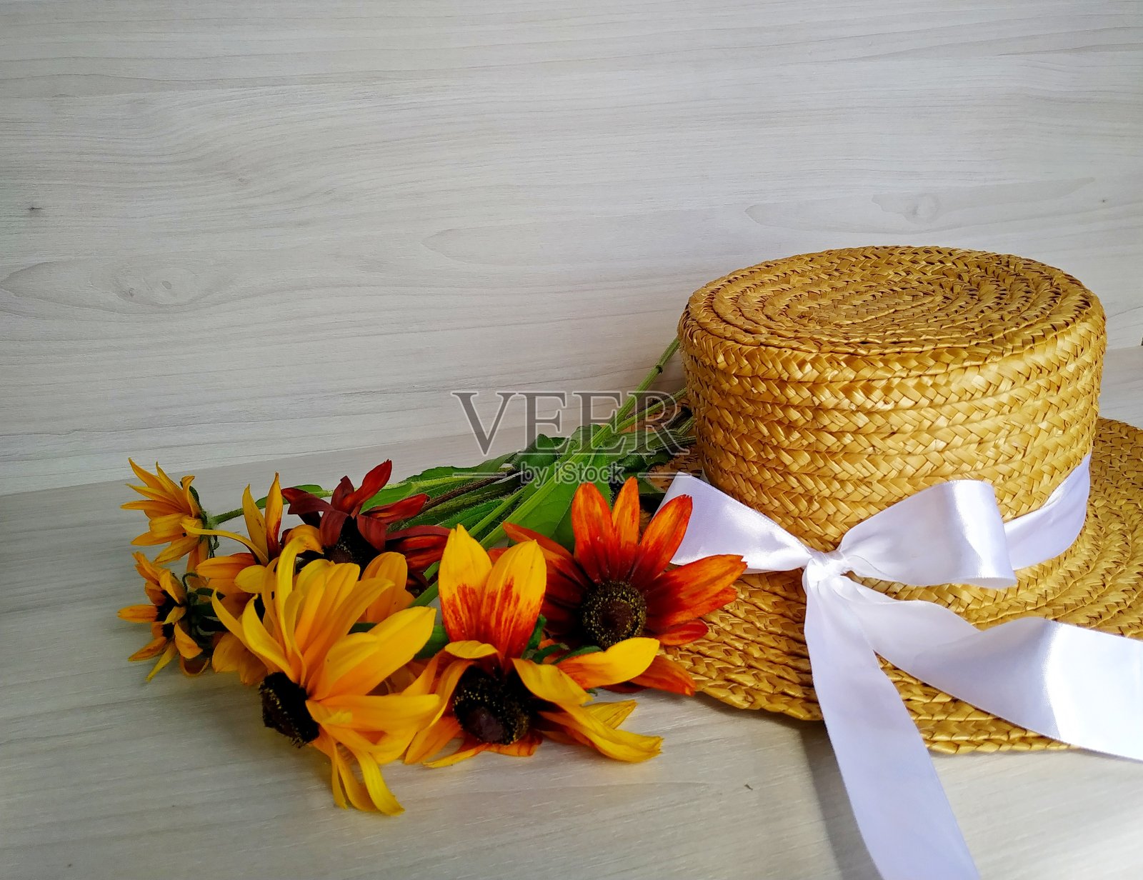 金色的双色白桦躺在柳条草帽上,背景是浅色的木头照片摄影图片