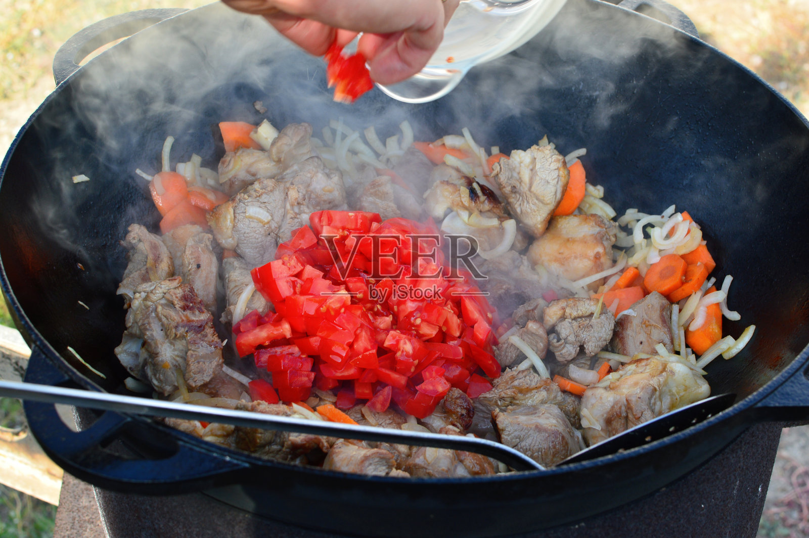 Shurpa、羊肉汤。白羊或牛肉什巴汤与蔬菜在一个大的铸铁锅上火煮过程。特写镜头。夏天徒步旅行的食物照片摄影图片