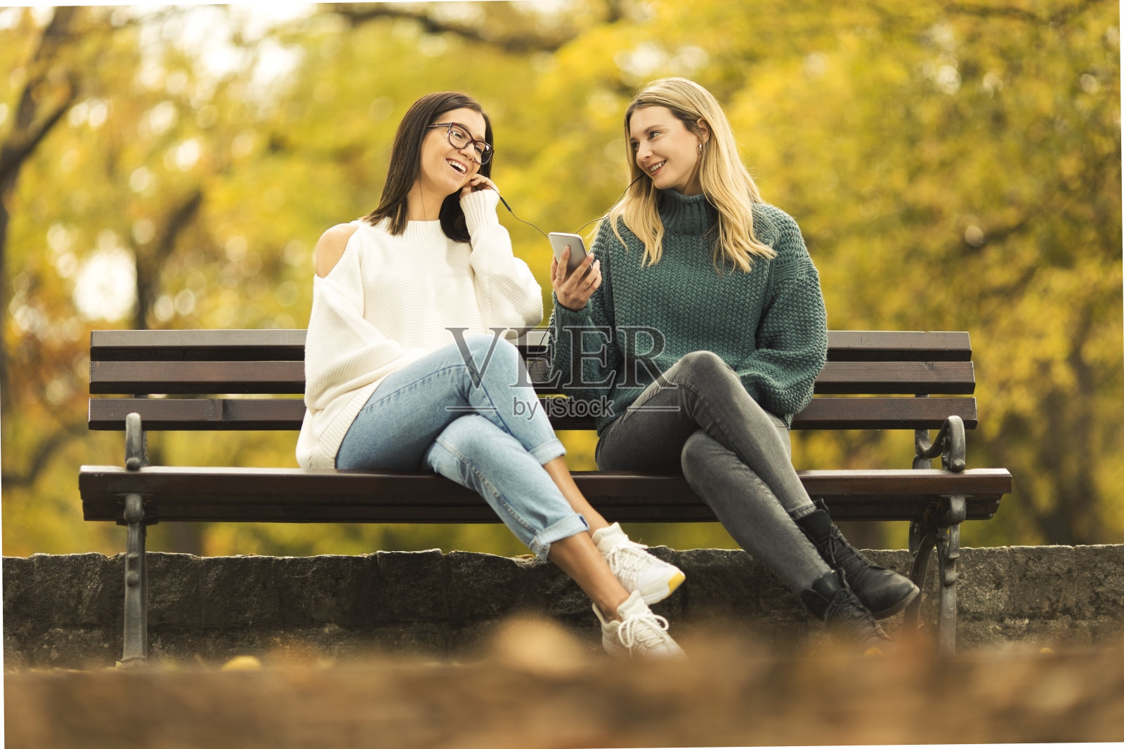 两个年轻女人坐在长凳上聊天照片摄影图片