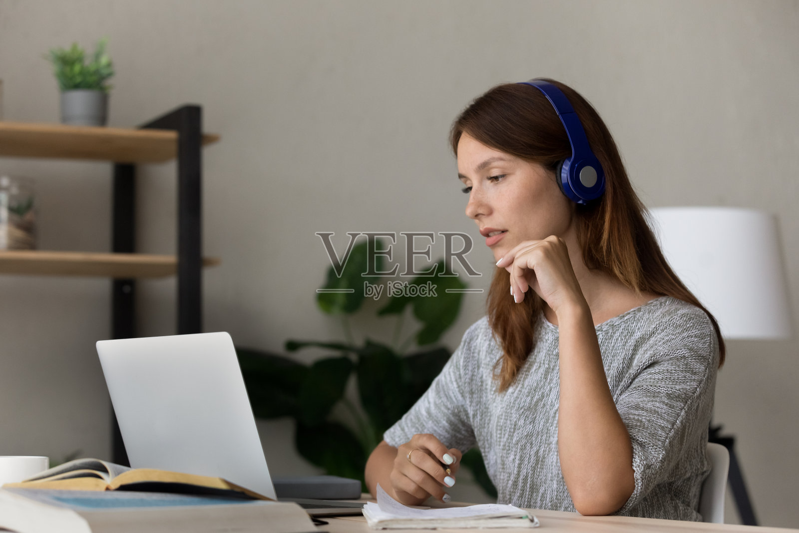 专注的女人戴着耳机在笔记本电脑上观看网络研讨会照片摄影图片