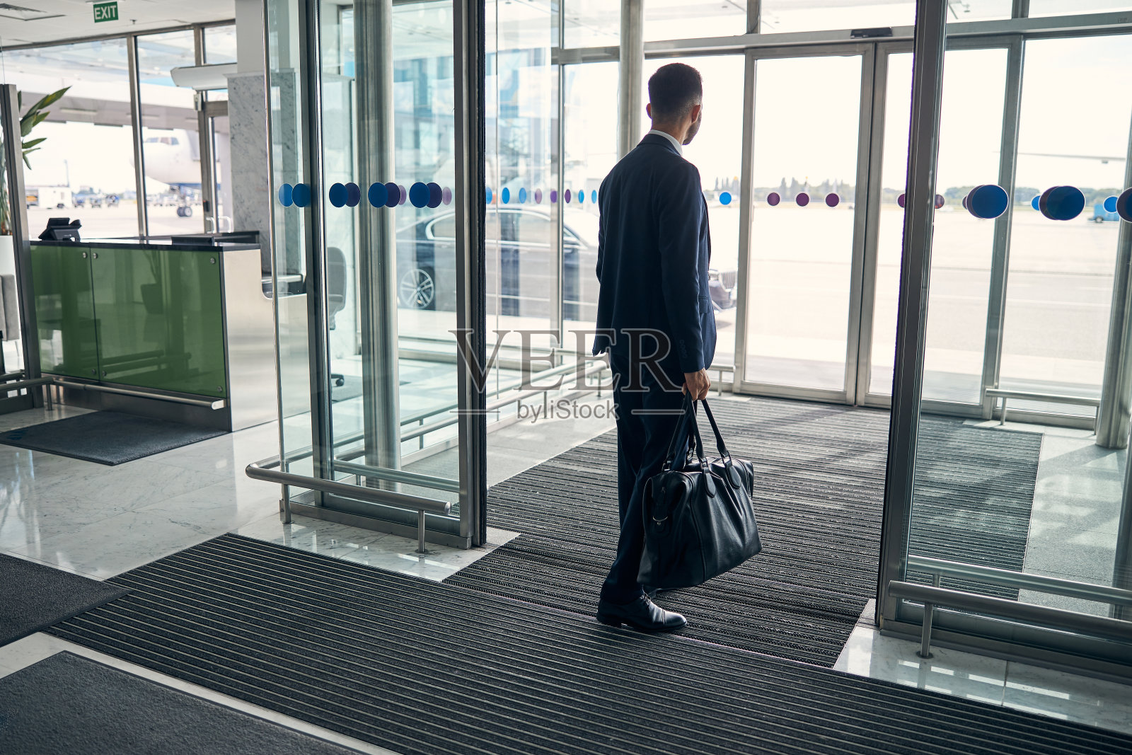 一个带着行李离开机场的年轻人照片摄影图片