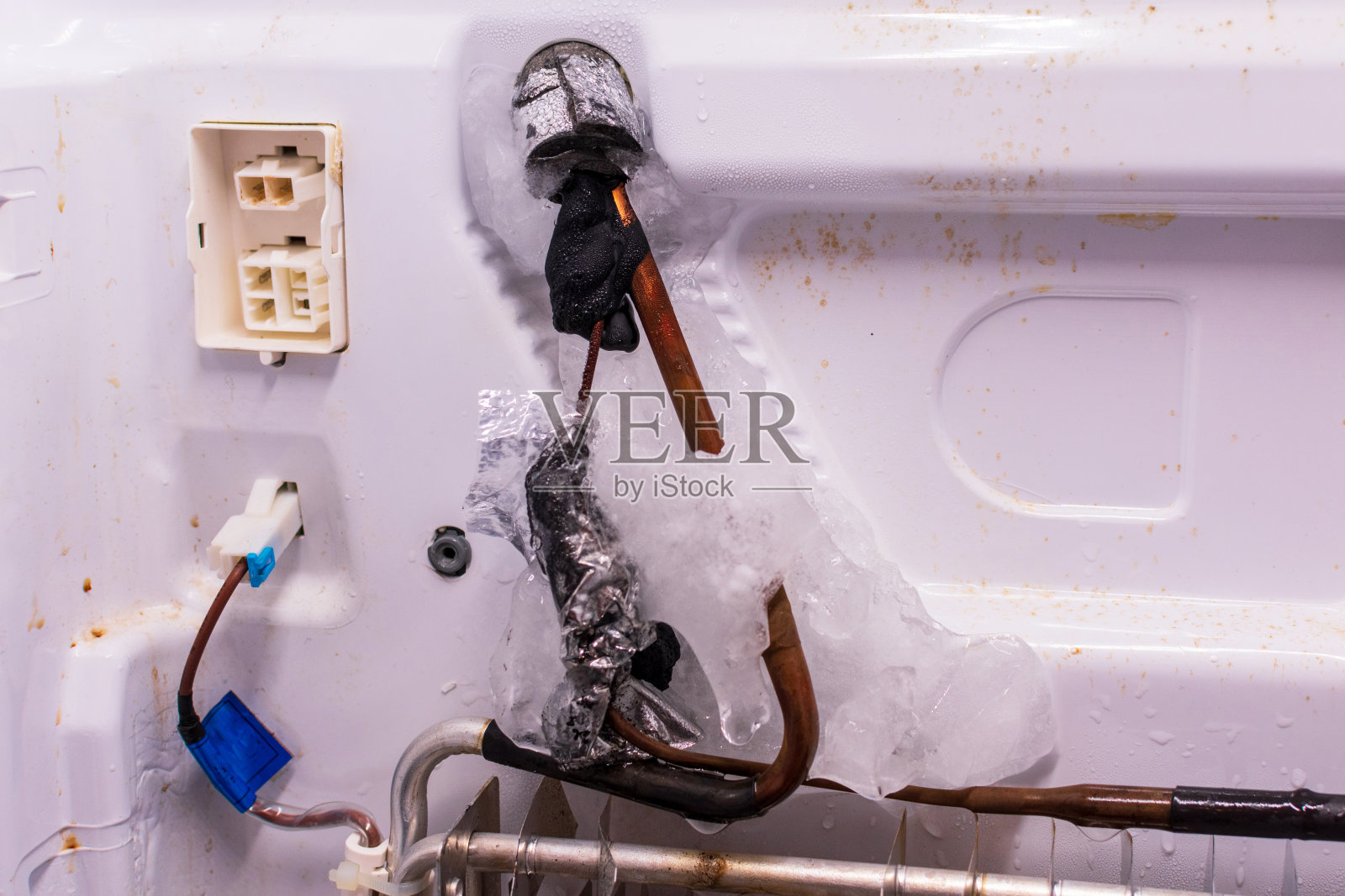 冰箱修理。冷冻室后面板拆除。蒸发器盘管与冷冻恒温器照片摄影图片