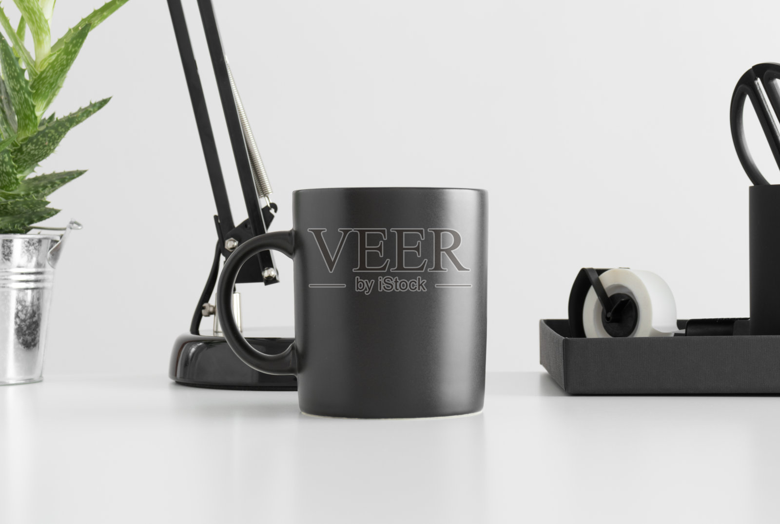 黑色马克杯模型与一盏灯,芦荟植物和工作配件在白色的桌子上。照片摄影图片