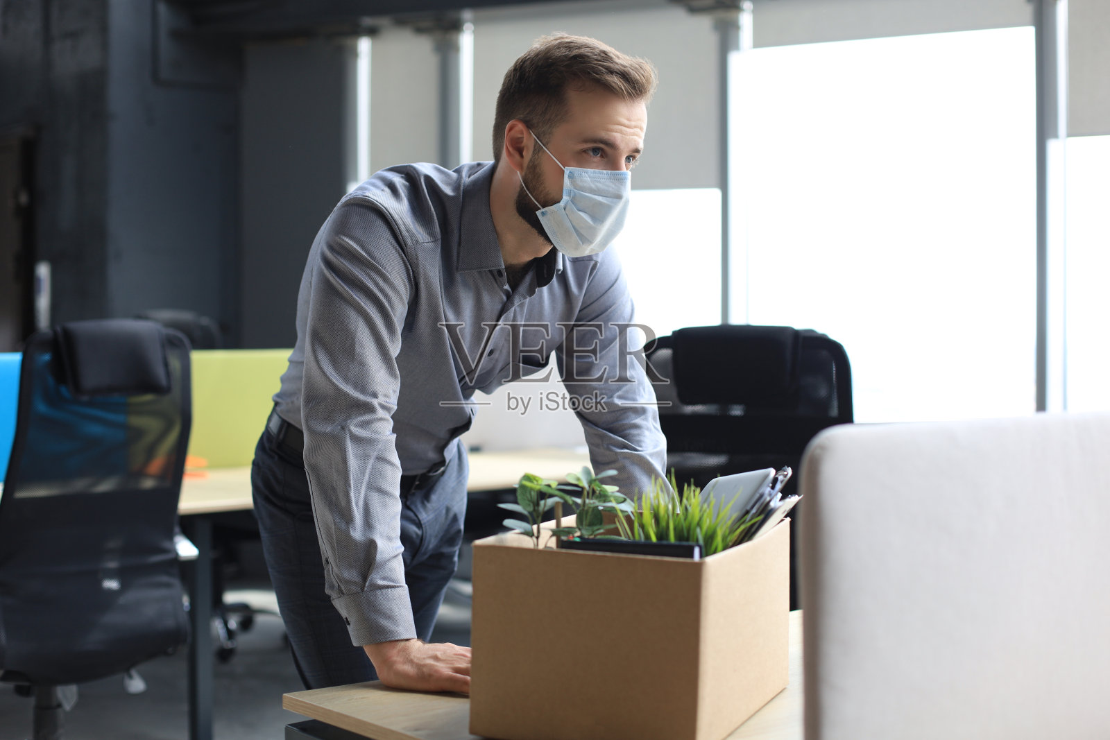 解雇冠状病毒感染的员工。伤心的被解雇的工人正带着办公用品离开办公室。照片摄影图片