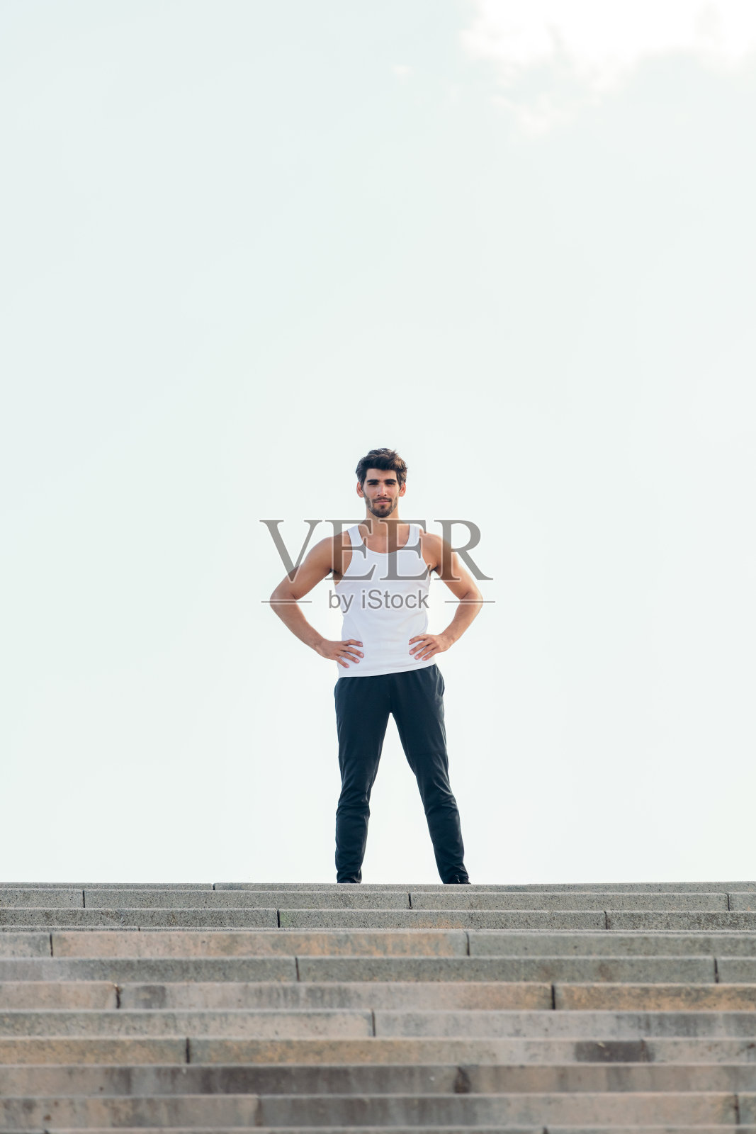 双手叉腰站在楼梯顶上的运动员照片摄影图片