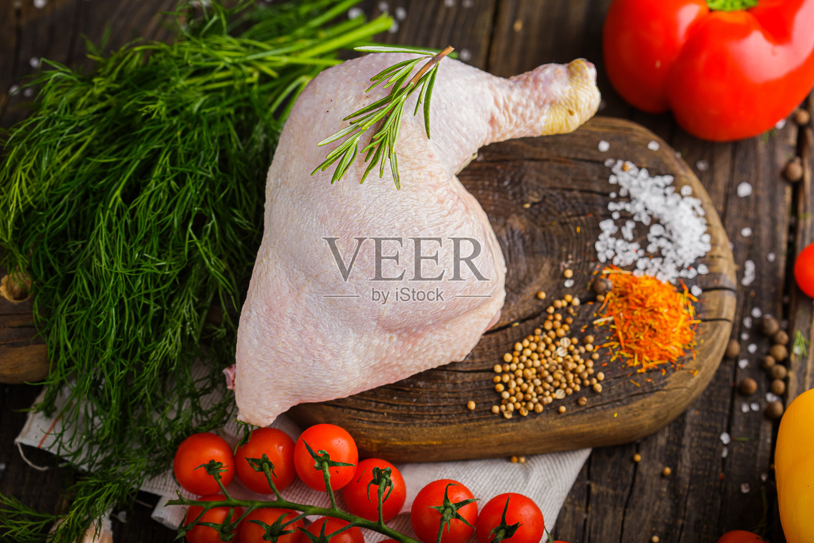 生鸡腿,鸡腿肉,香料和粗盐,乡村风格,樱桃番茄枝,在黑色的背景照片摄影图片