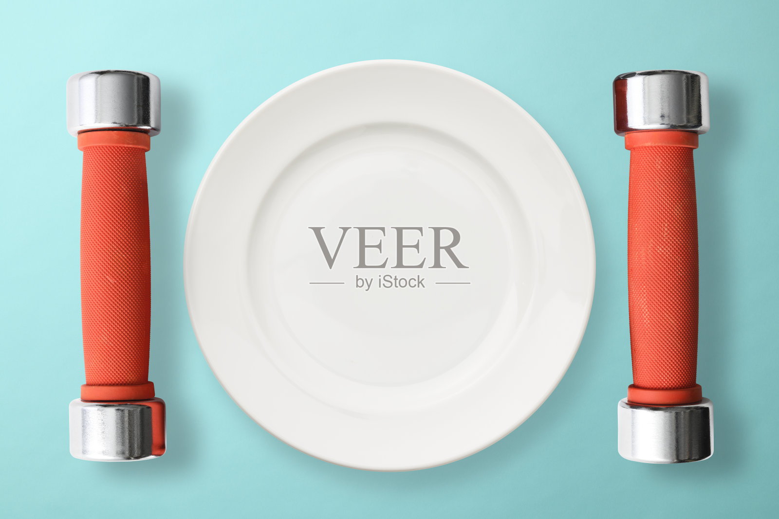 红色哑铃旁边的白色盘子,浅蓝色的背景照片摄影图片