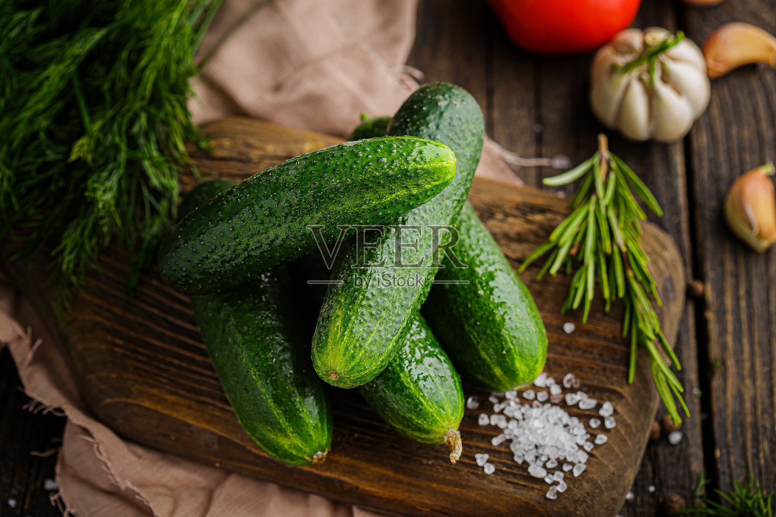 全绿黄瓜,滴上香料和粗盐,乡村风格,绿色,樱桃番茄枝,在黑色的背景上照片摄影图片
