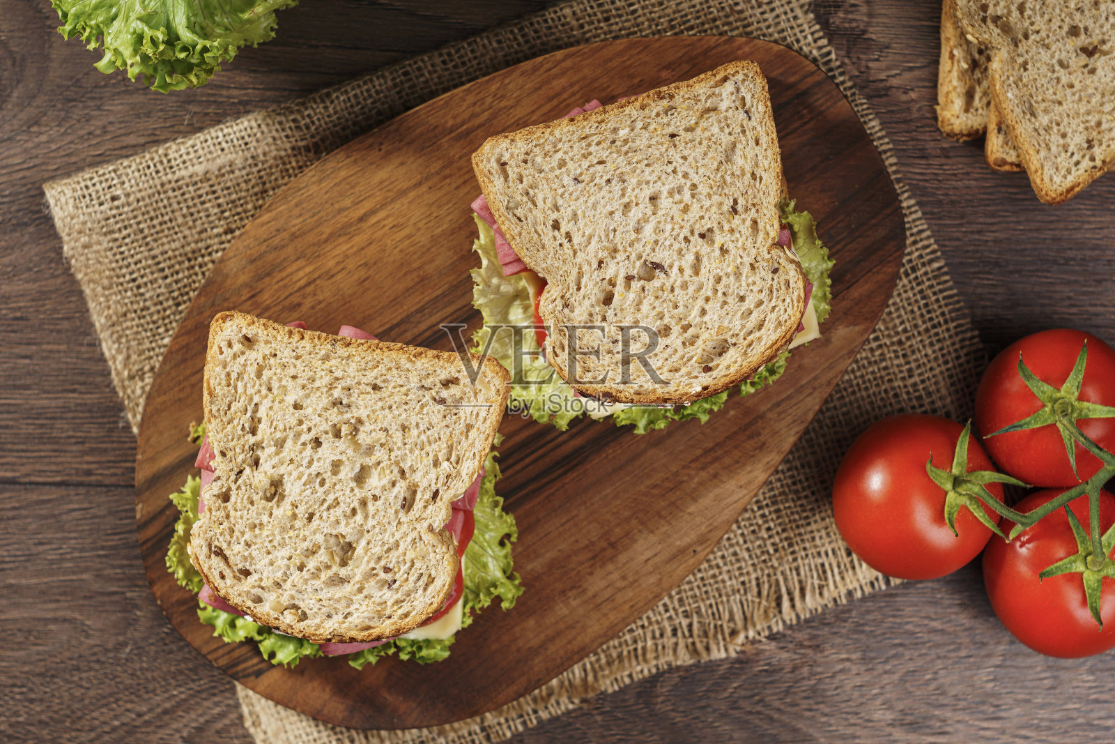 全谷物面包三明治配意大利腊肠,番茄,奶酪和新鲜生菜照片摄影图片
