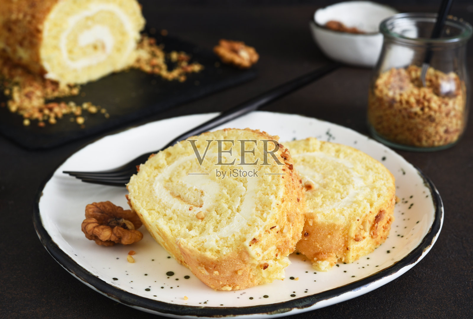 在一个黑色背景的碗里有奶油和坚果的饼干卷。照片摄影图片