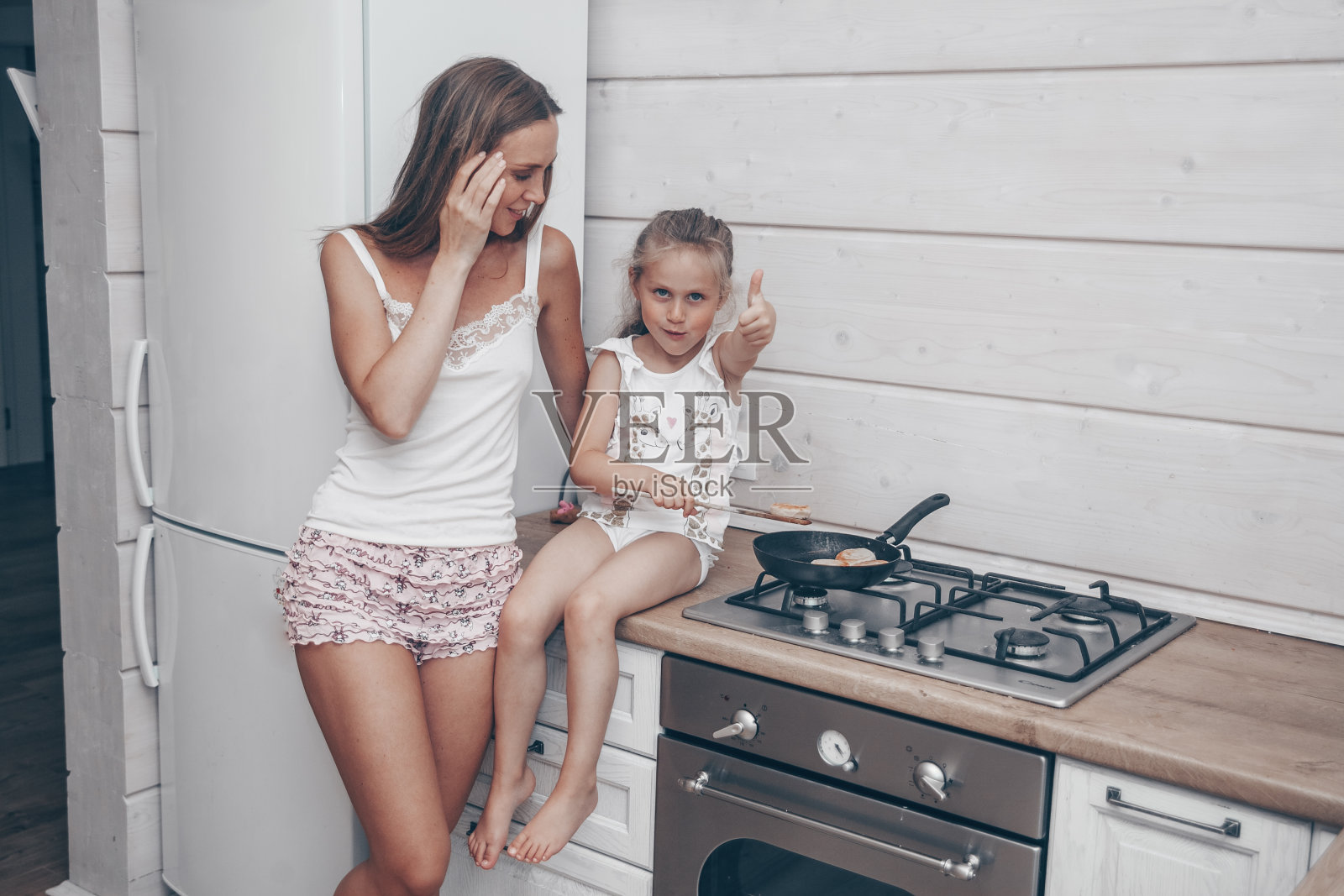 幸福的一家人一起为早餐准备起司蛋糕。美丽的年轻妈妈和她可爱的女儿女孩做饭和在厨房里玩。自制健康的食物,没有帮手。照片摄影图片