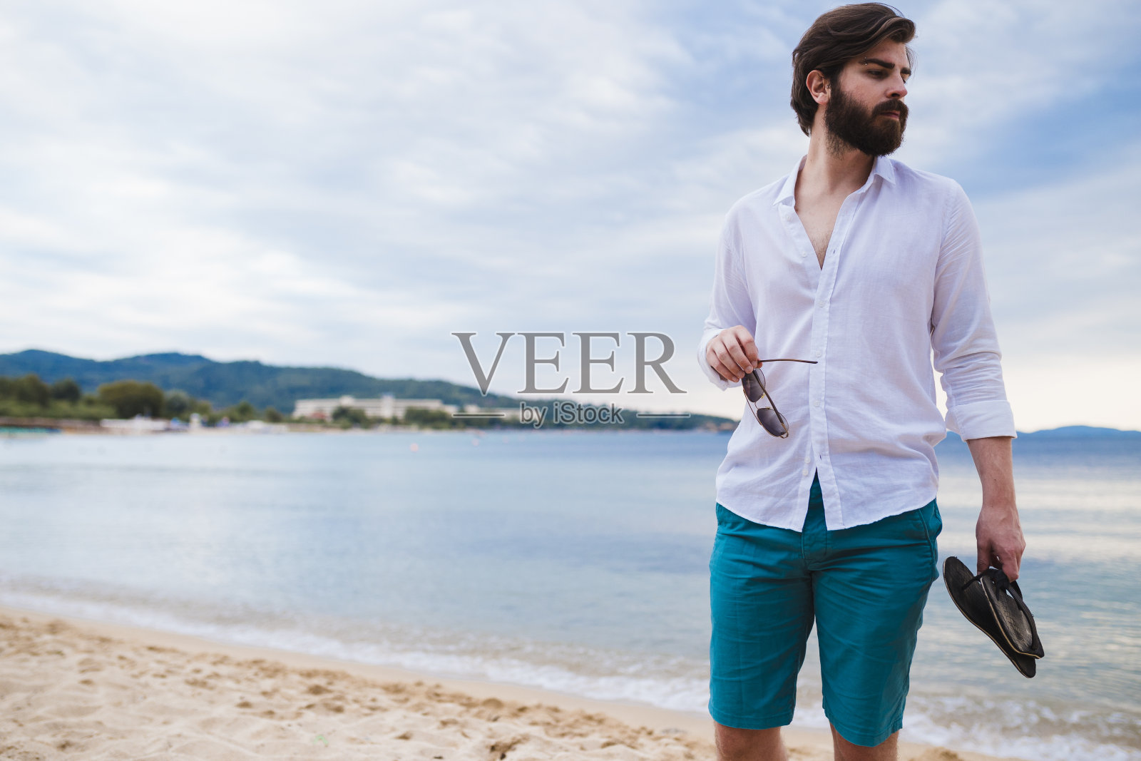 在一个阳光明媚的夏日,一个年轻人在海滩上散步照片摄影图片