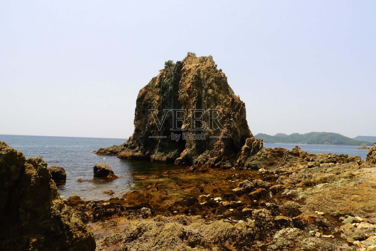 陡峭的岩石高耸向海岸照片摄影图片