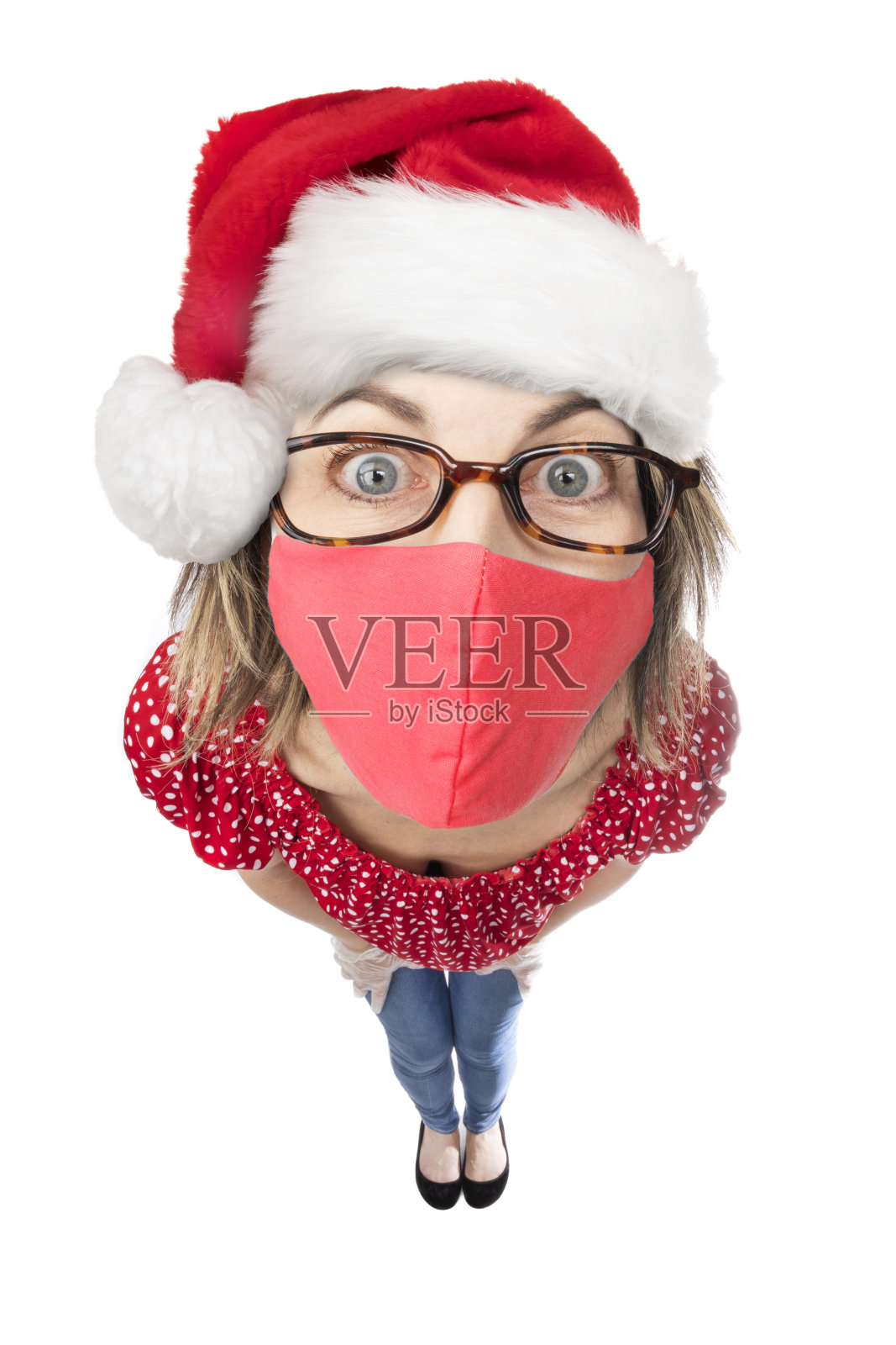 戴着圣诞帽和冠状病毒面具的鱼眼有趣女人照片摄影图片