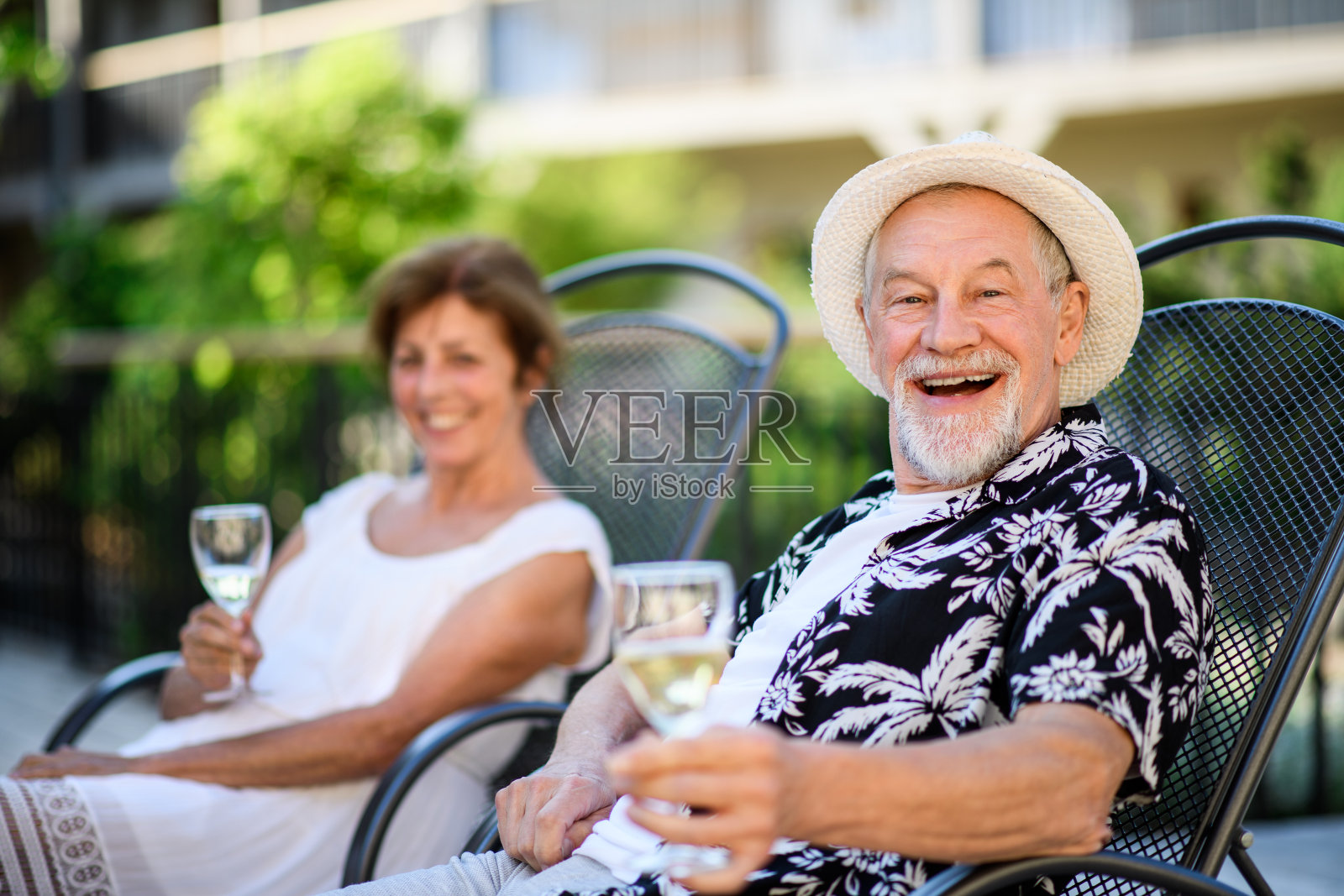 一对老年夫妇拿着酒在户外度假,看着相机。照片摄影图片