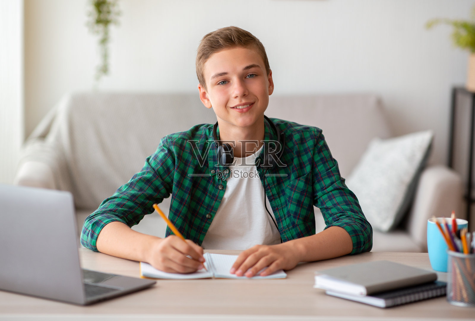快乐的男孩做作业,坐在桌子前,用笔记本电脑照片摄影图片