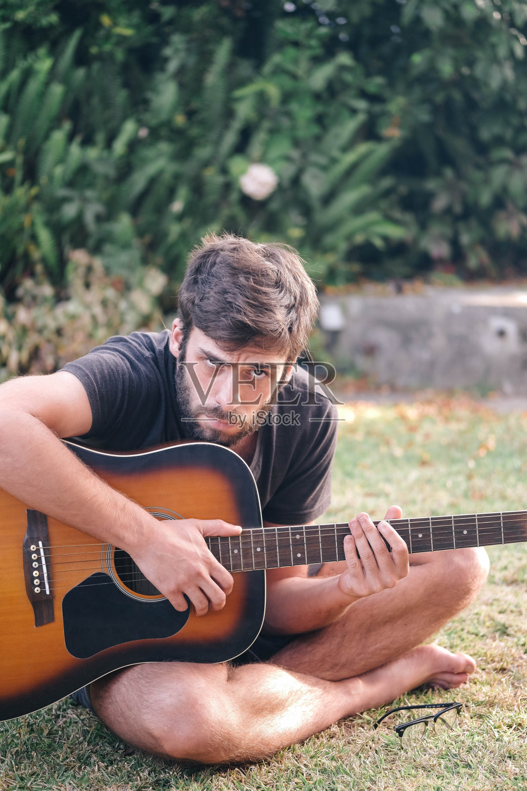 一个年轻人正在公园里弹吉他照片摄影图片
