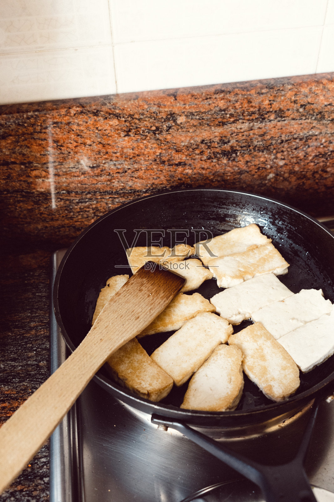 豆腐在黑色平底锅中煸炒照片摄影图片