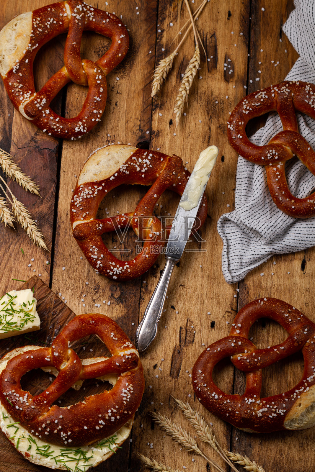 德国布列泽尔椒盐卷饼,黄油在木制背景。Butterbrezel照片摄影图片