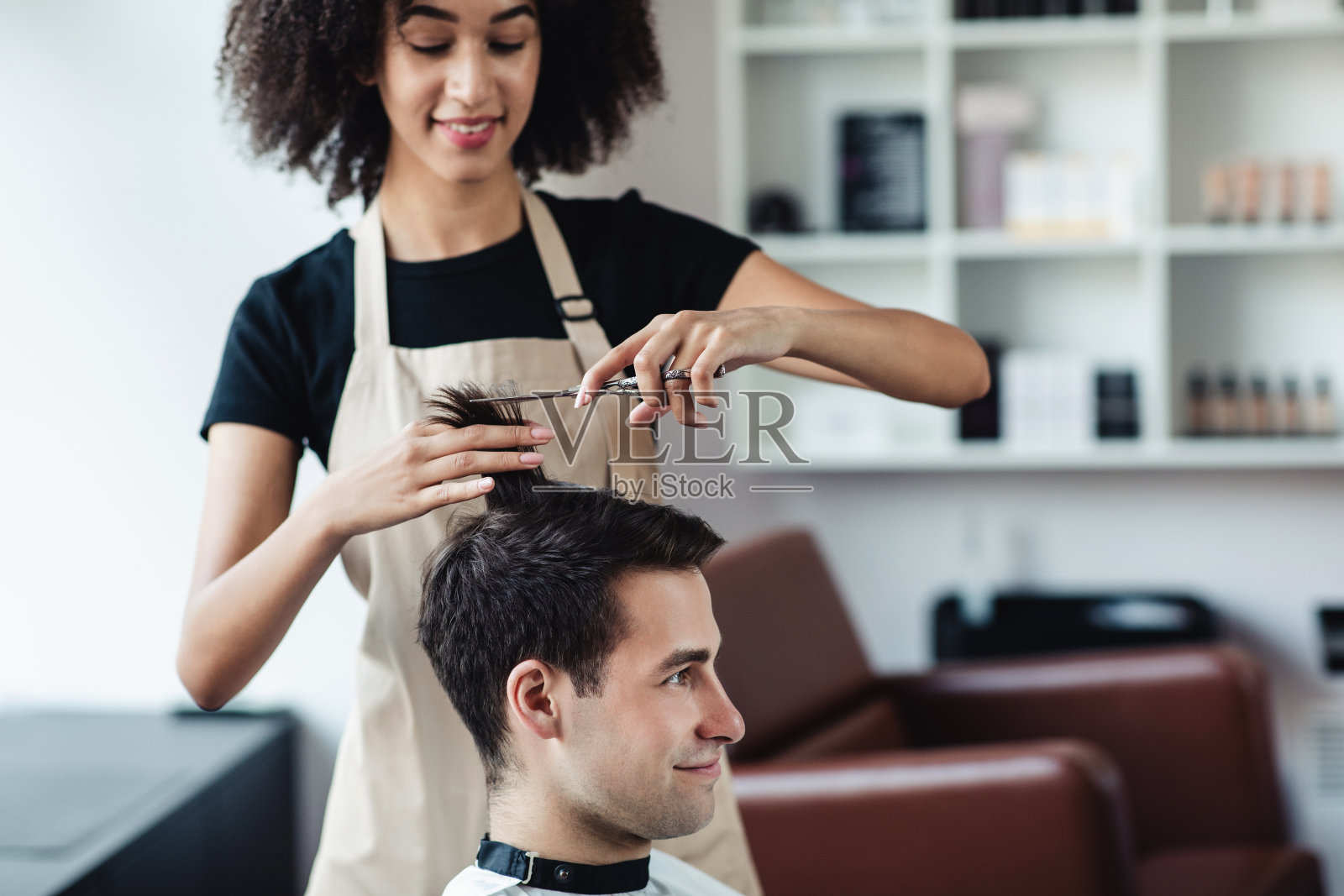 一位非裔美国美发师在理发店为年轻人理发照片摄影图片