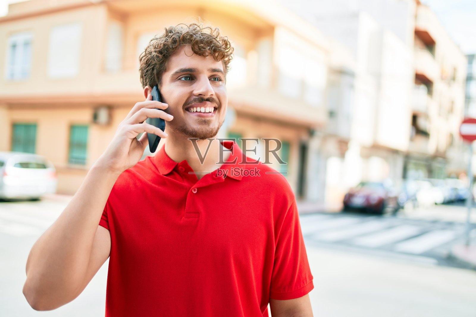 年轻英俊的白人男人笑得很开心。在城市里用智能手机聊天。照片摄影图片