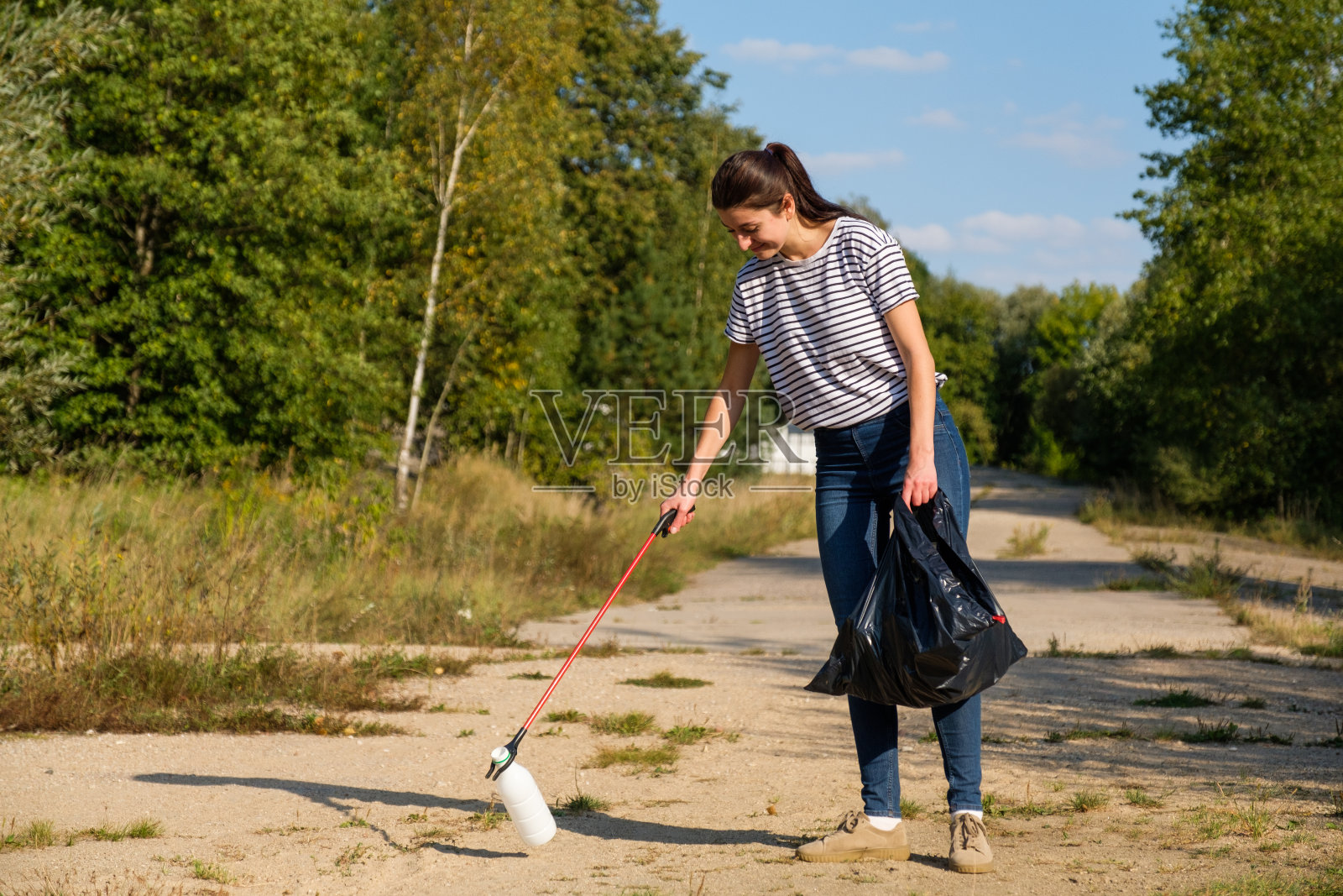 志愿者妇女在森林里捡塑料垃圾。清洁环境的概念照片摄影图片
