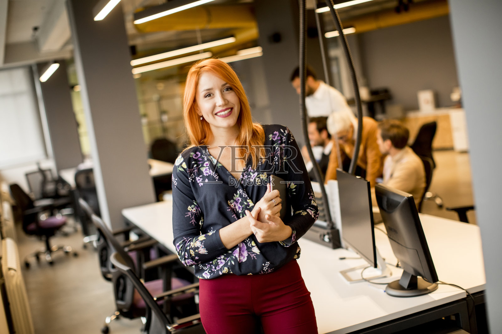 年轻的女商人拿着一个数字平板电脑,在现代办公室的后台团队工作照片摄影图片