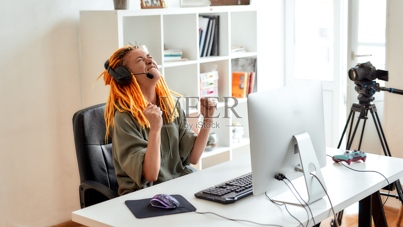 我做到了。女电竞玩家,戴着耳机的女人看起来很兴奋,获胜,在电脑上玩在线视频游戏,白天录制视频照片摄影图片