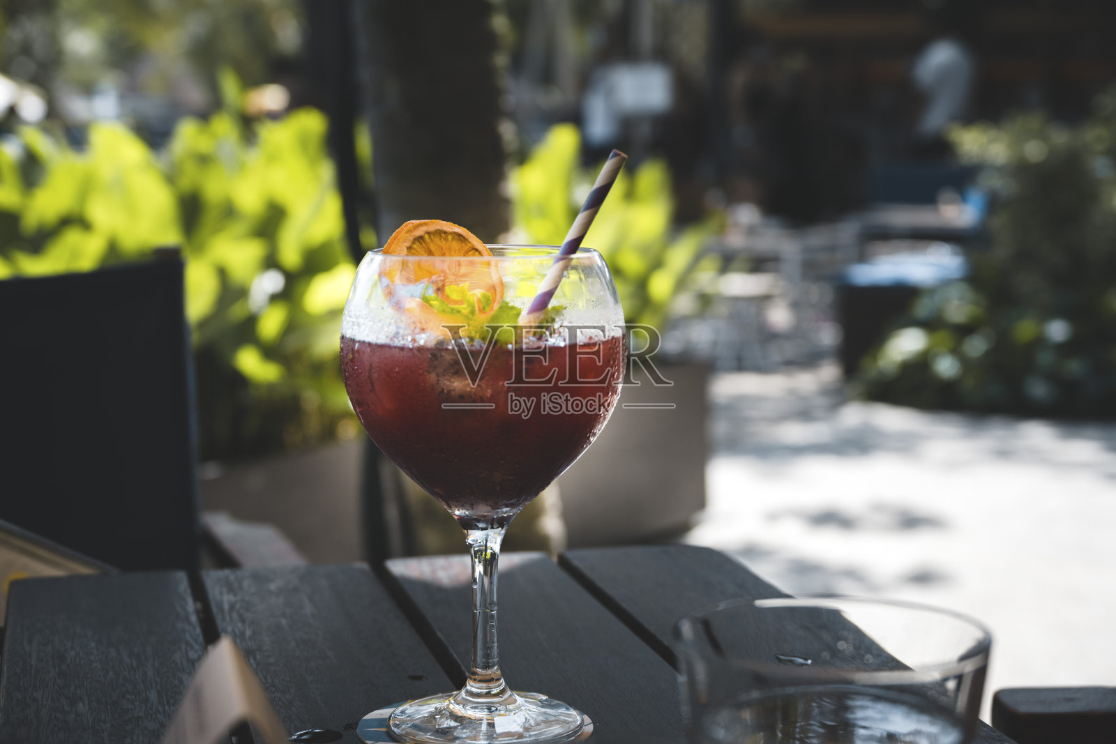 杯中的红色鸡尾酒放在户外的桌子上照片摄影图片