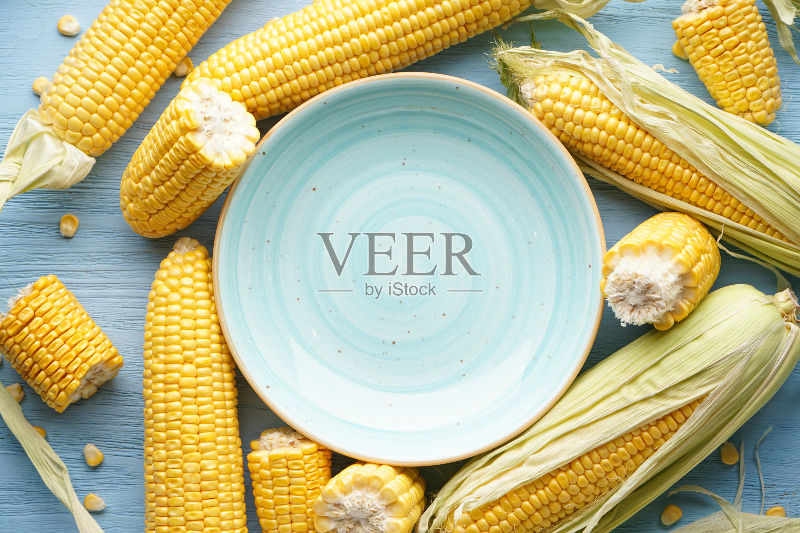 新鲜的玉米在棒子和盘子上的木制背景,放置文字。前视图。照片摄影图片